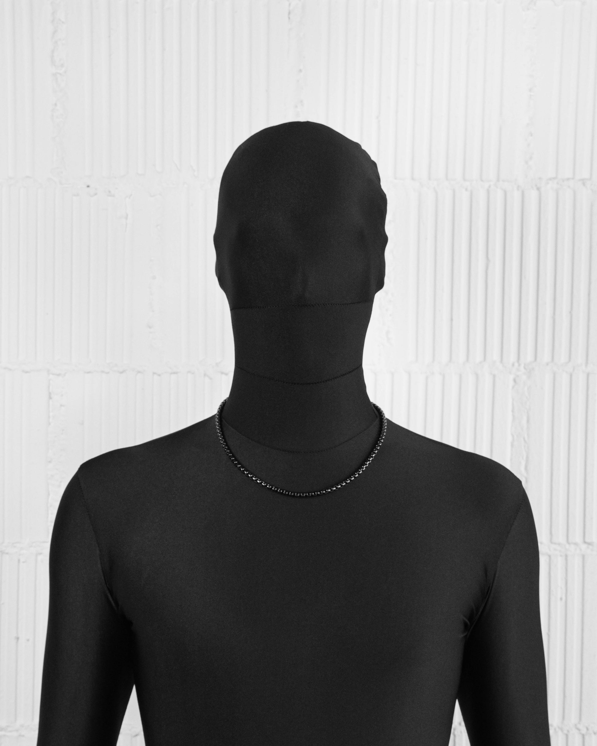 man with black suit wearing black PVD coated box chain necklace with lasered logo lobster clasp