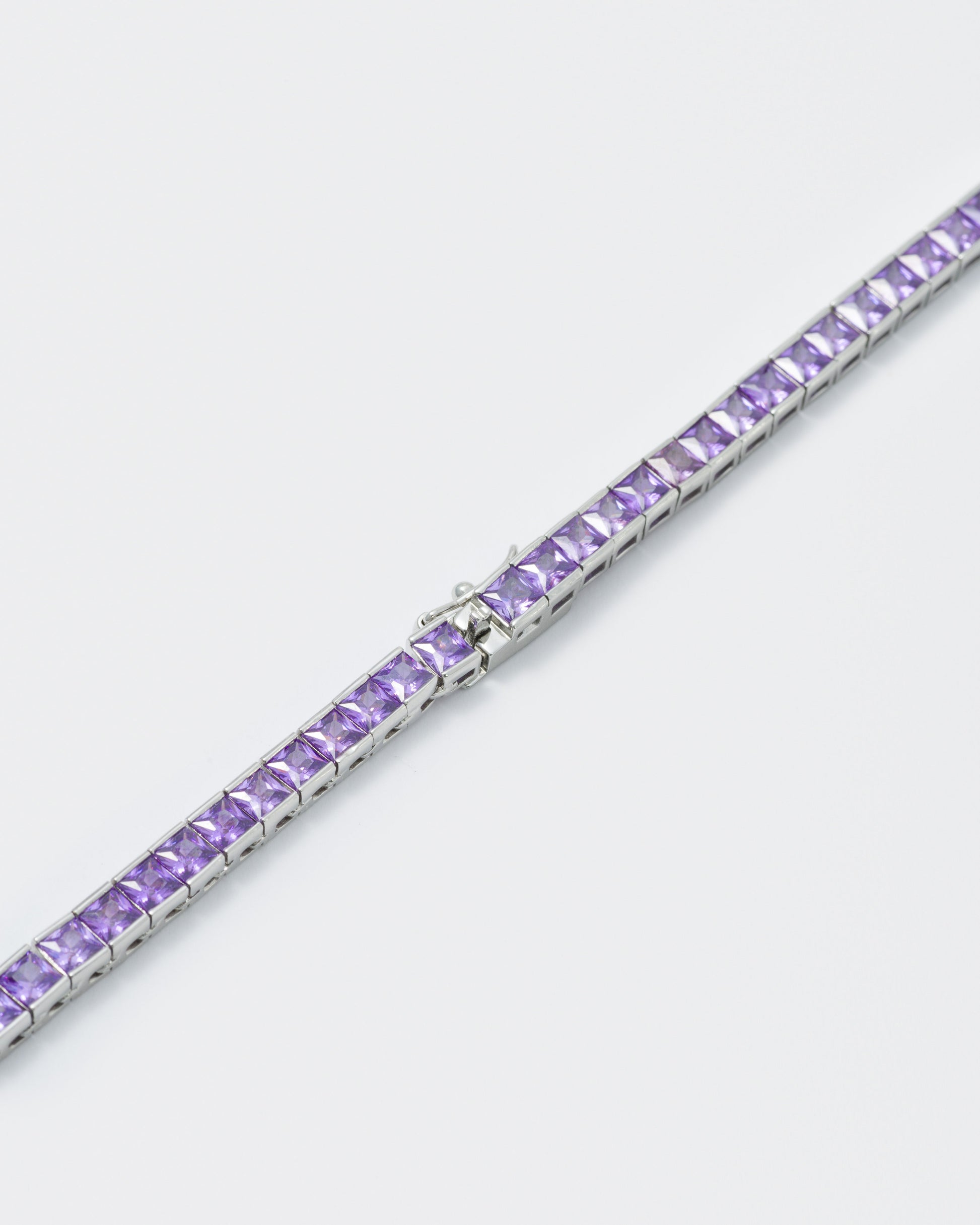 detail of 18k white gold coated tennis chain necklace with hand-set princess-cut stones in amethyst purple