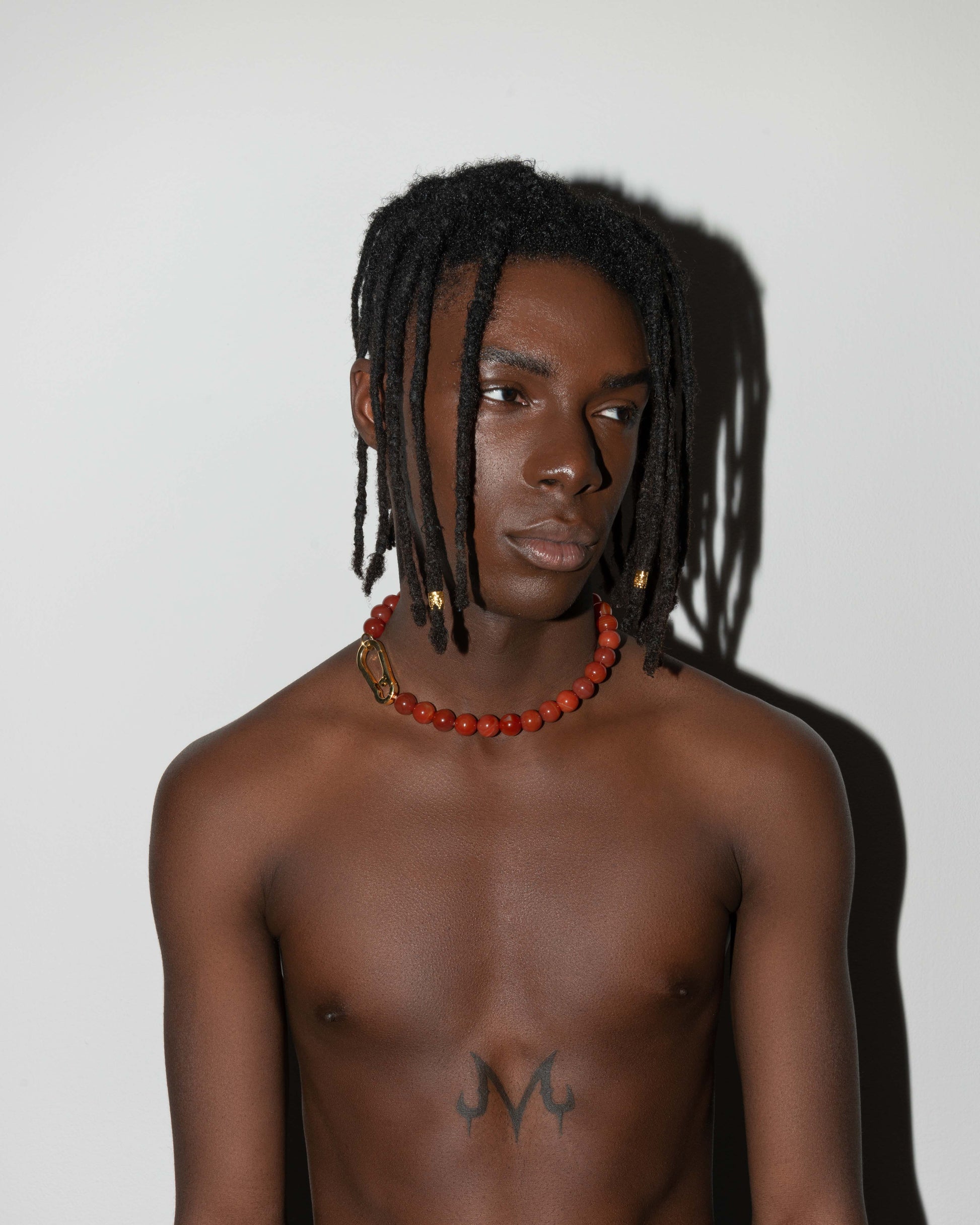 street style man wearing Amber stones necklace with 18k yellow gold coated lasered logo oversize carabiner clasp