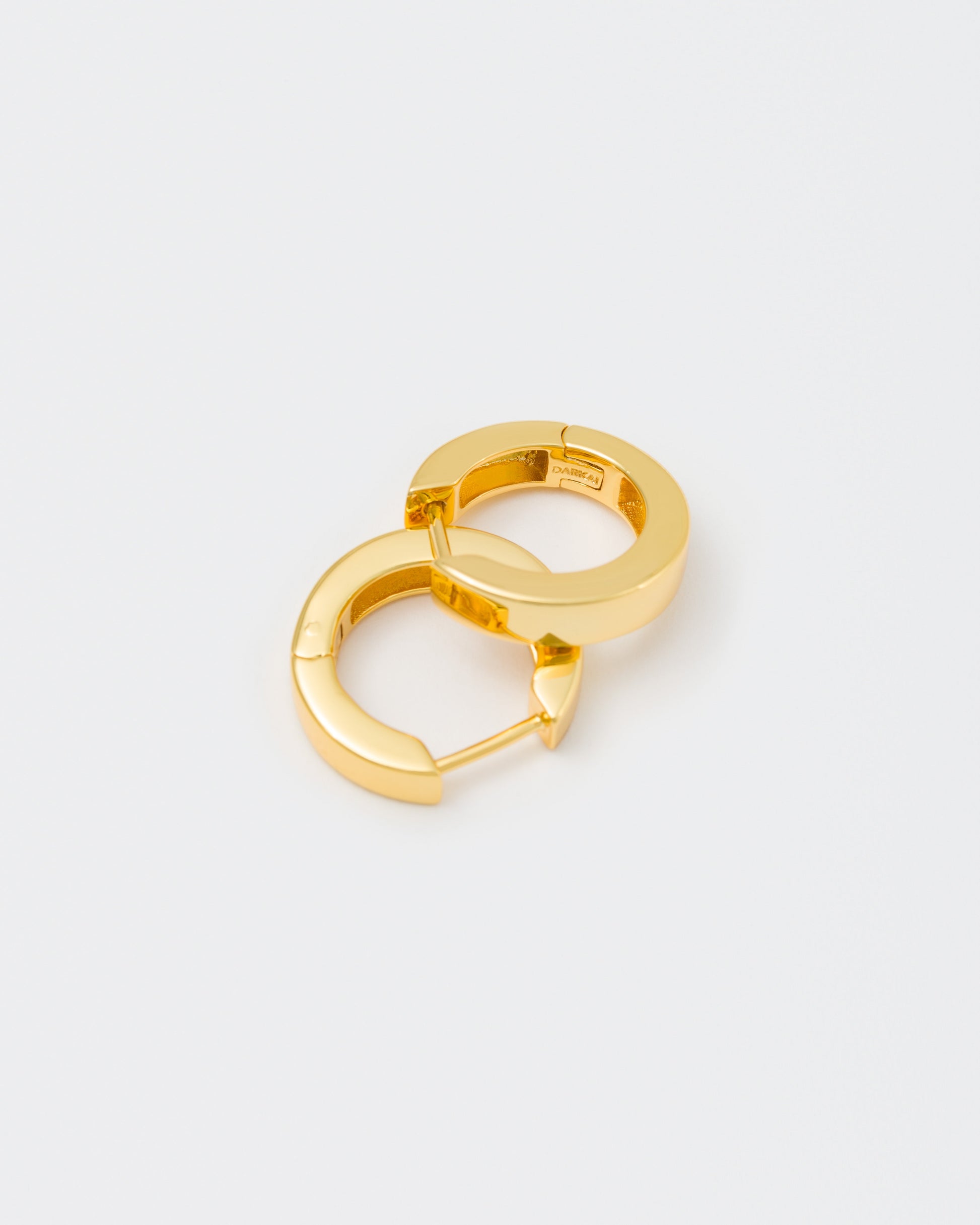 detail of 18k yellow gold coated hoop earrings with lasered logo and details on the inside