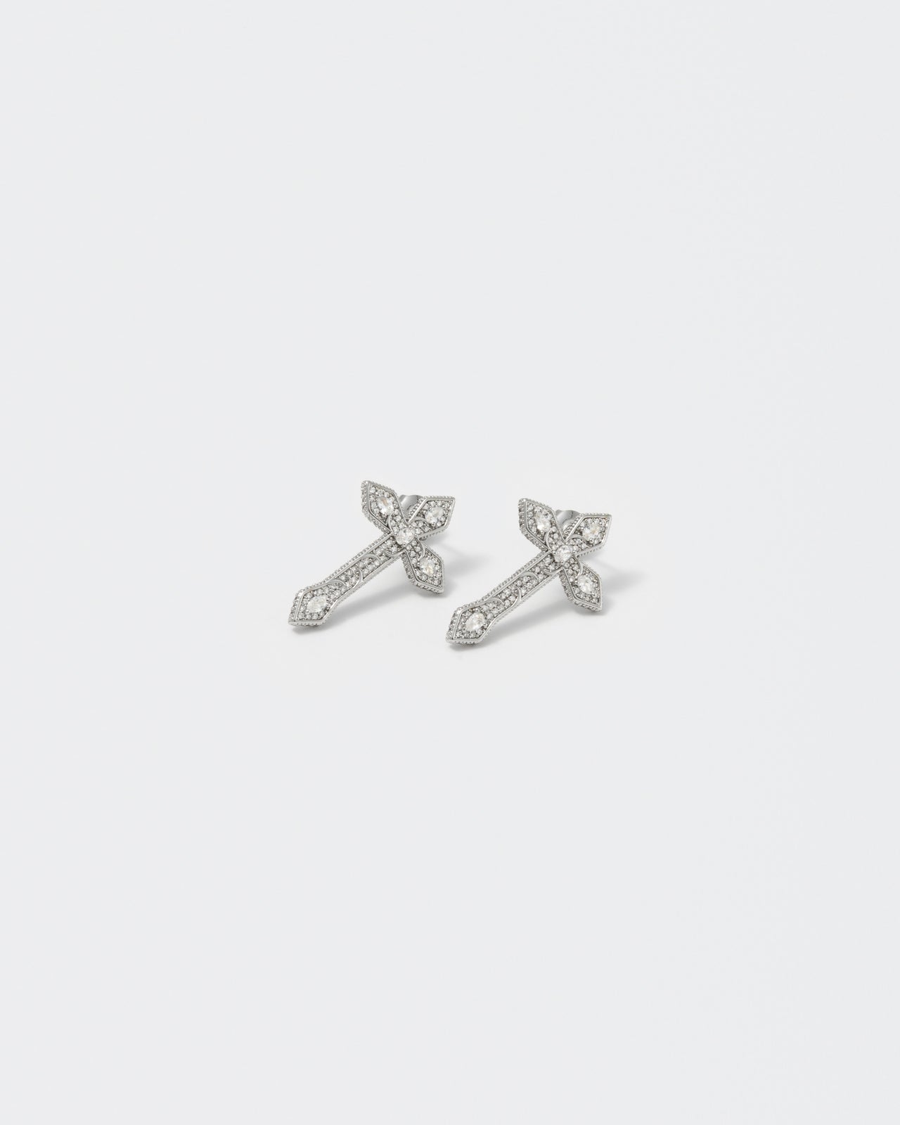 gothic cross earrings with 18kt white gold coating, drop and oval shaped diamond white stones with metal gothic detailing. Hand-set micropavé on front and sides. Silver 925 pin and butterly closure with logo.