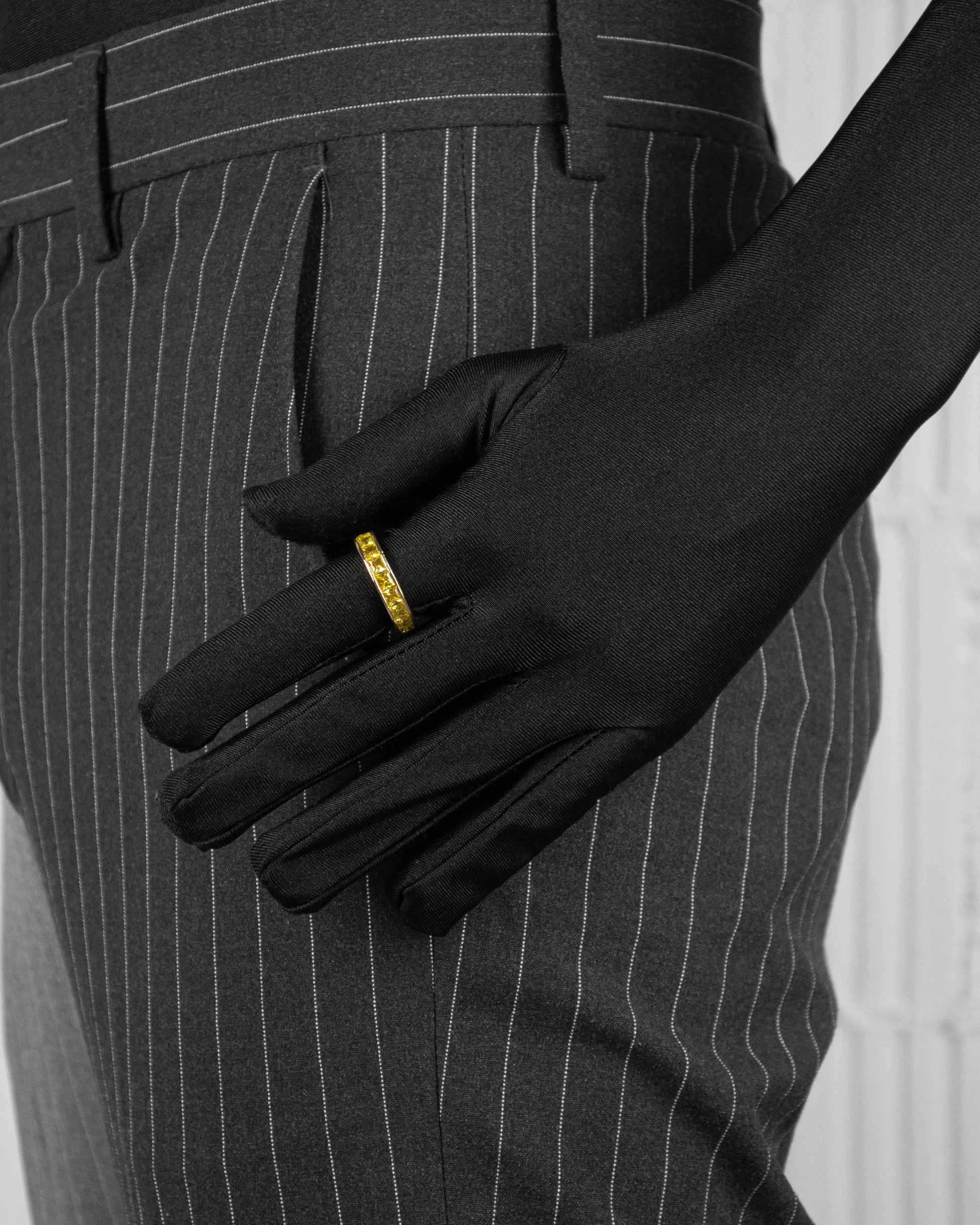 man with black suit wearing yellow ring with stones