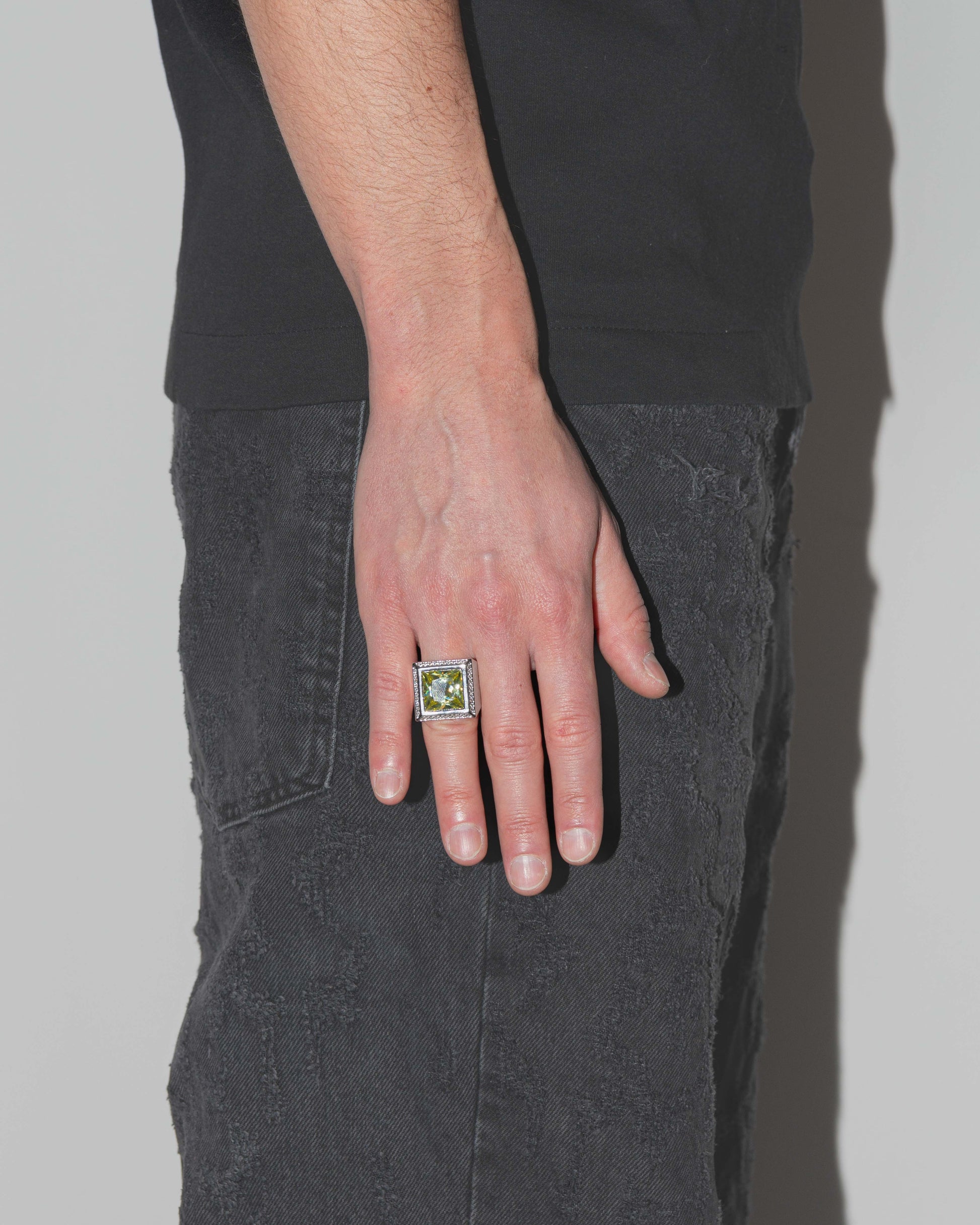 man wearing championship ring with 18kt white gold coating, oversize princess-cut stone in olive with hand-set diamond white zircons on the frame
