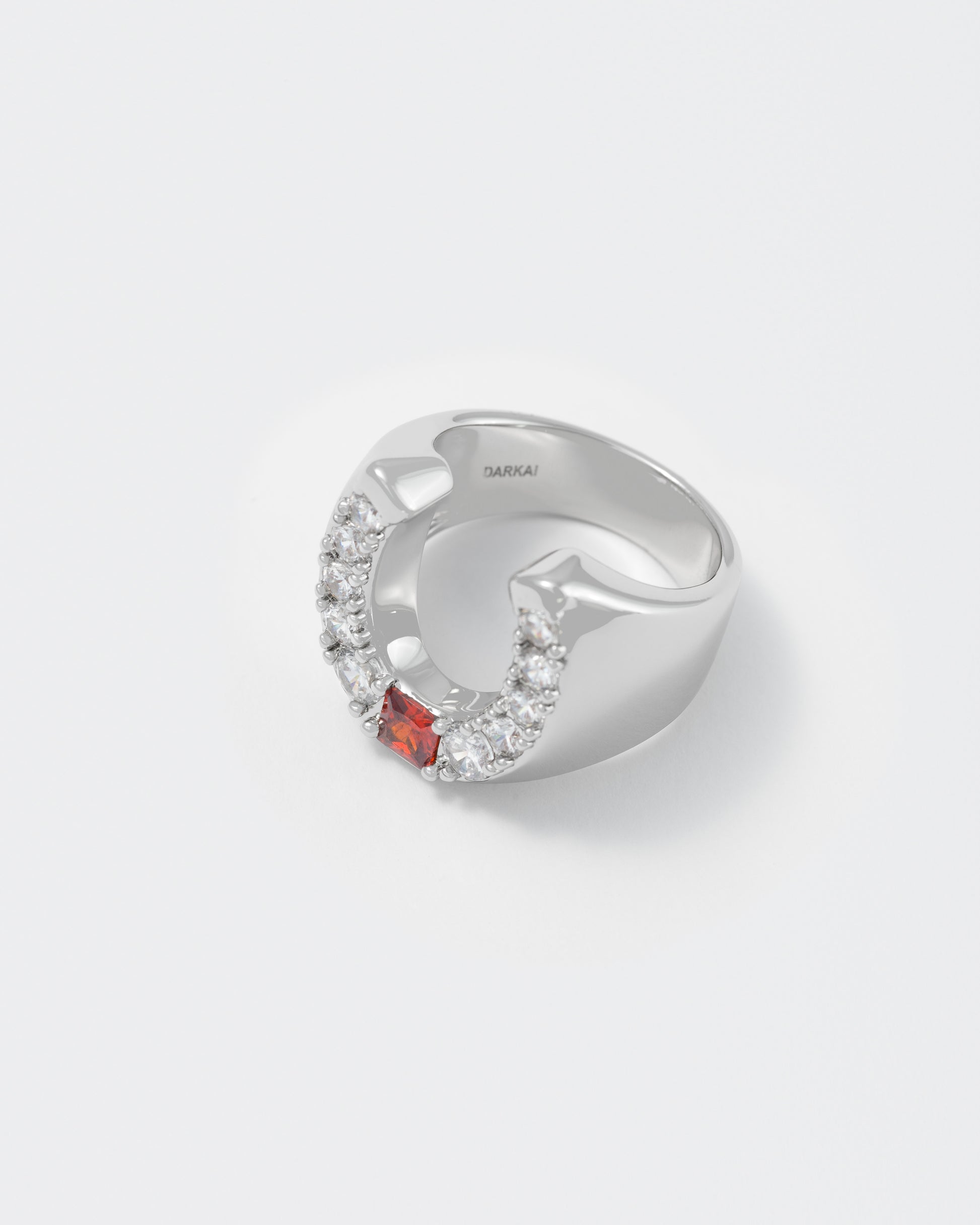 detail of horseshoe ring with 18kt white gold coating and round shaped brilliant-cut diamond white stones with central princess-cut garnet stone