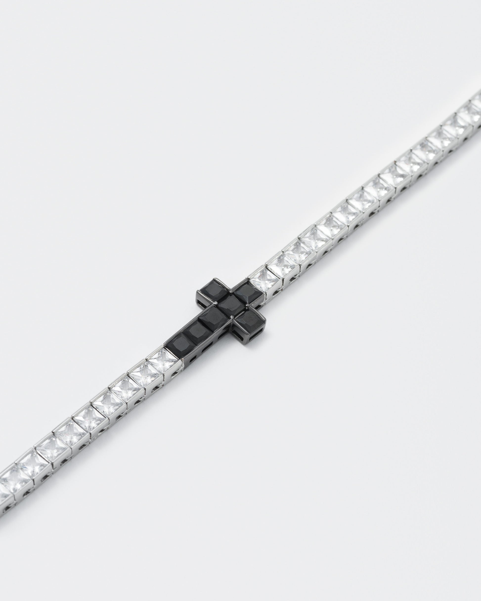 detail of 18k white gold and black coated tennis chain bracelet with contrasting cross element and hand-set princess-cut stones in white and black