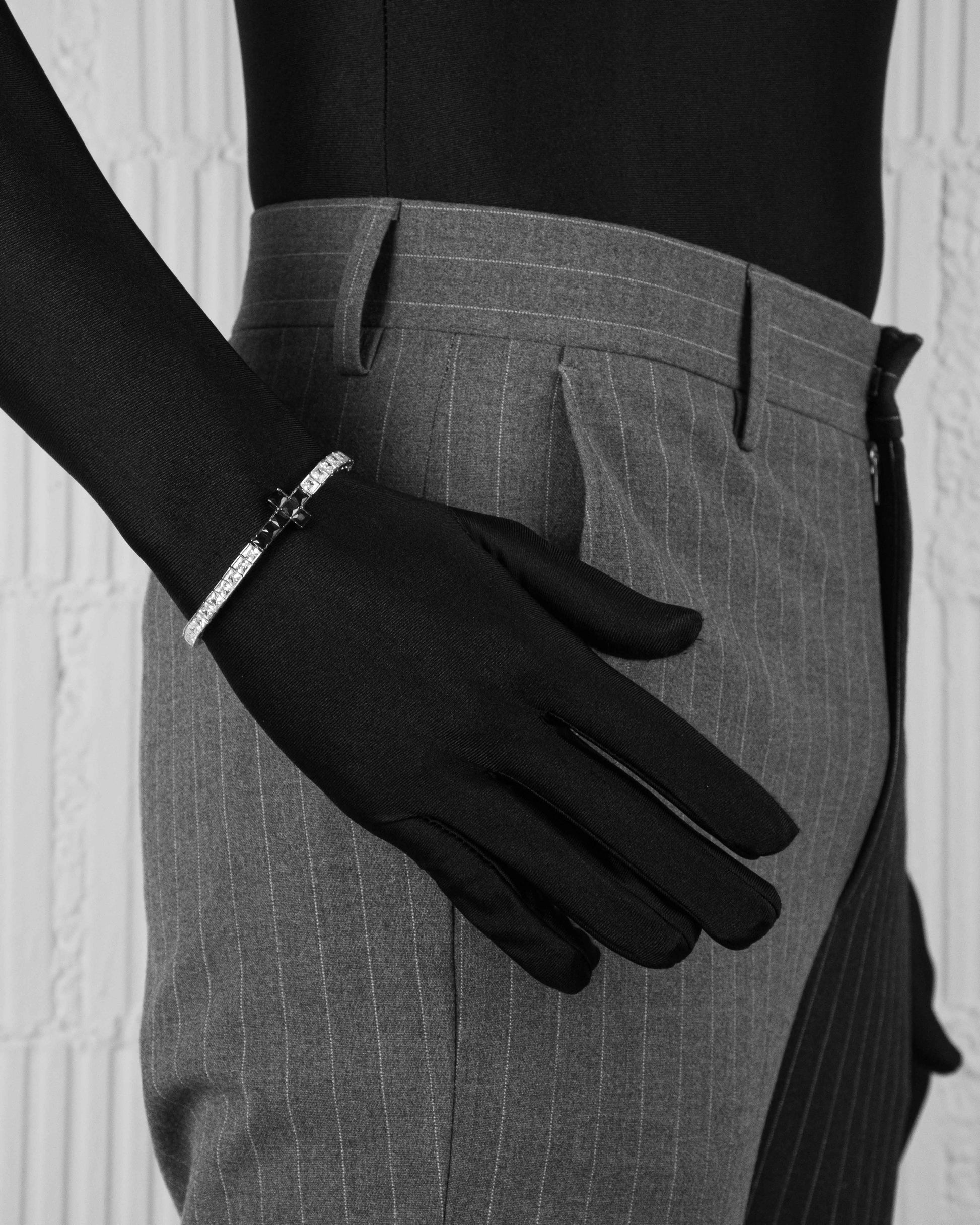 man with black suit wearing white tennis chain bracelet with black cross element and hand-set princess-cut stones in white and black