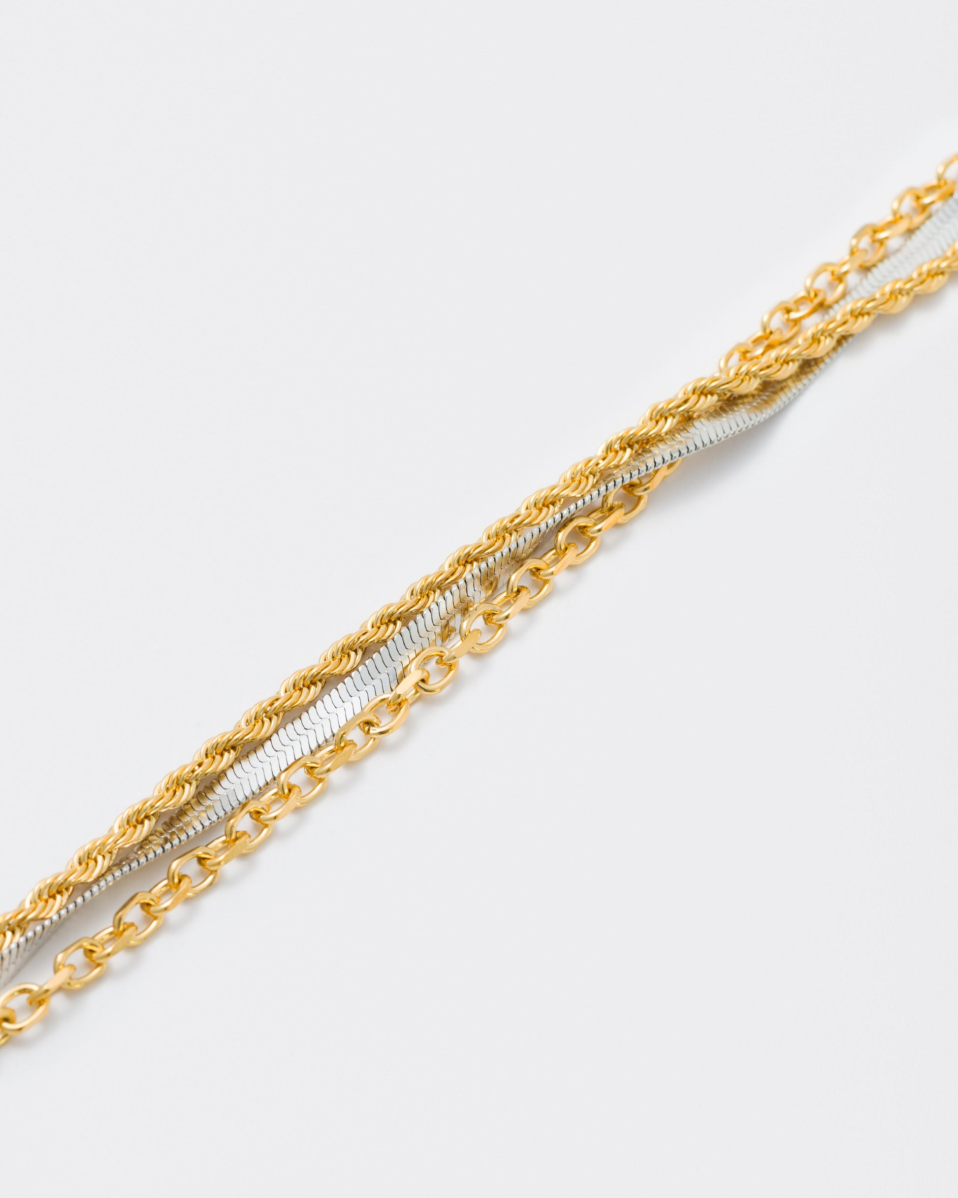 detail of yellow and white gold coated 3 layers bracelet with 3mm rope and cable chain and contrasting 4mm herringbone chain