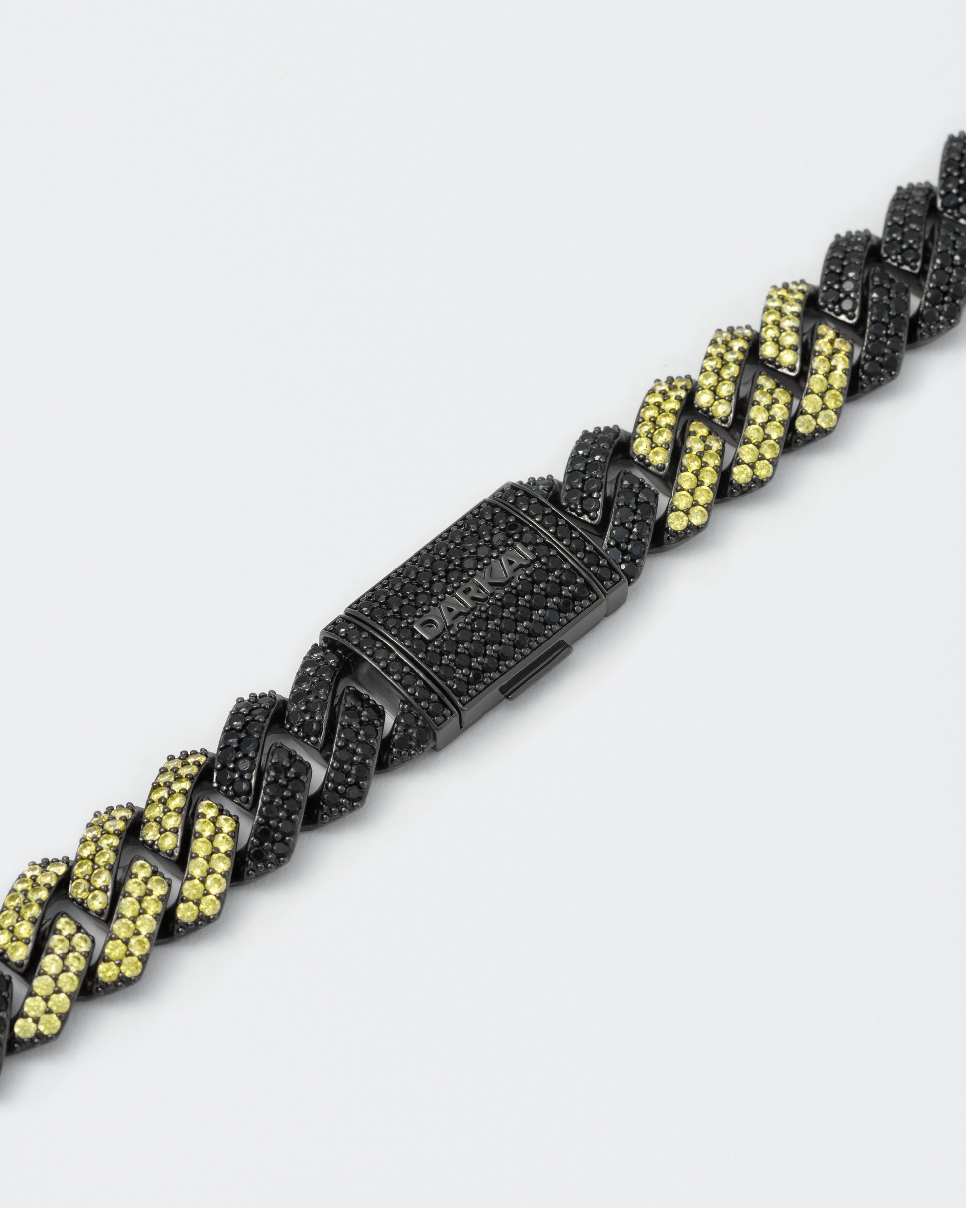 detail of prong chain bracelet with deep black PVD coating and hand-set micropavé stones in black and golden yellow. Fine jewelry grade drawer closure with logo