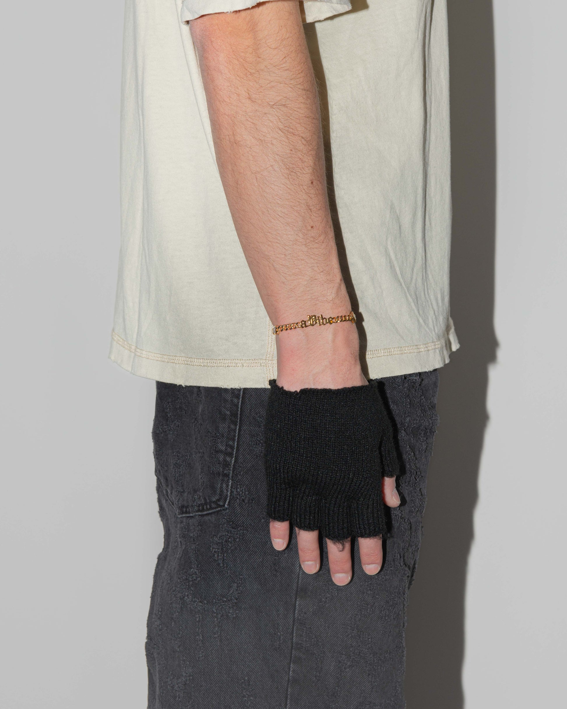 man wearing a vibe cuban chain bracelet with 18kt yellow gold coating, mixed shape bezel stones in diamond white, yellow, garnet, tanzanite and "A Vibe" central metal tag