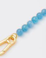 detail of Aquamarine stones bracelet with 18k yellow gold coated lasered logo oversize carabiner clasp.