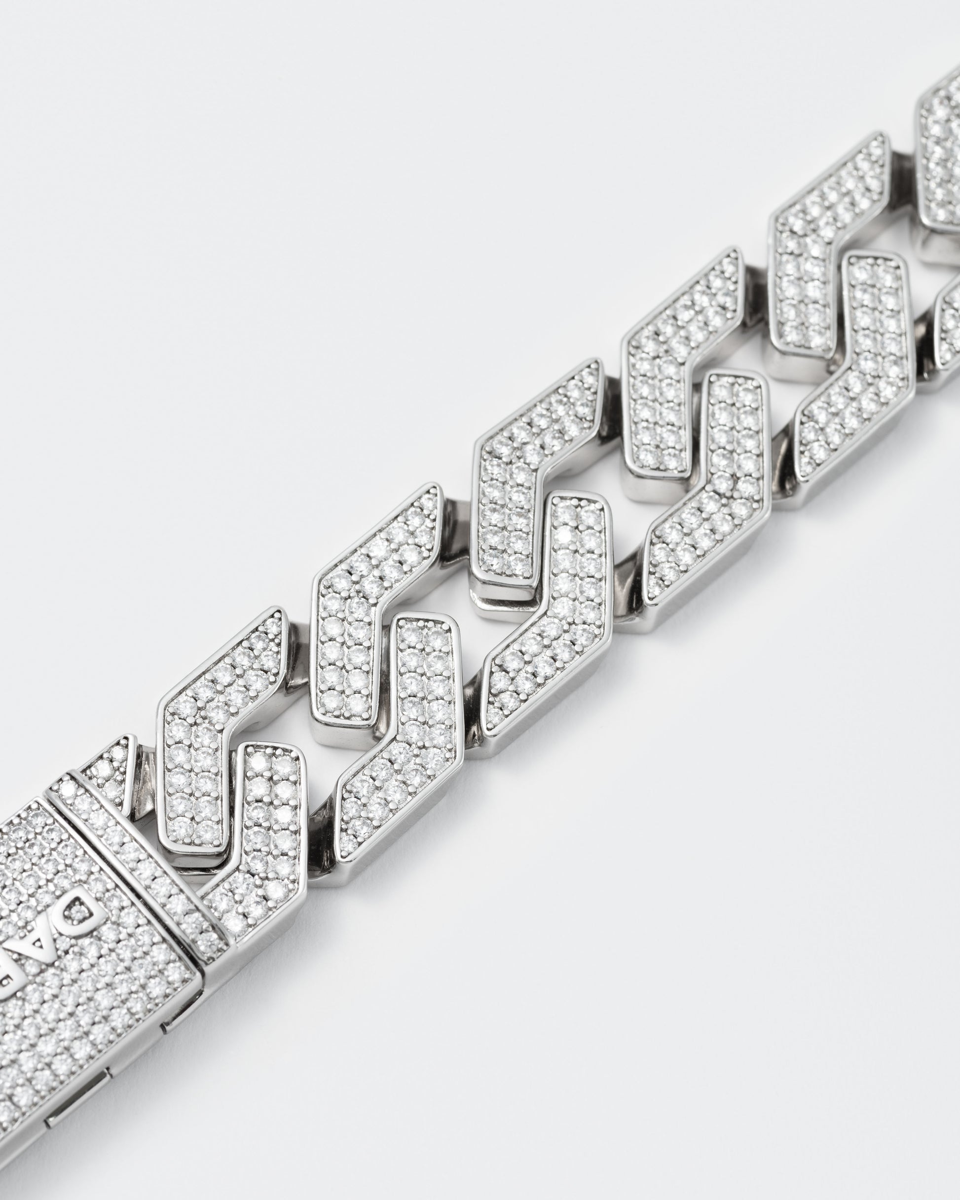 detail of oversize prong chain bracelet with 18kt white gold coating and hand-set micropavé stones in diamond white. Fine jewelry grade drawer closure with logo.