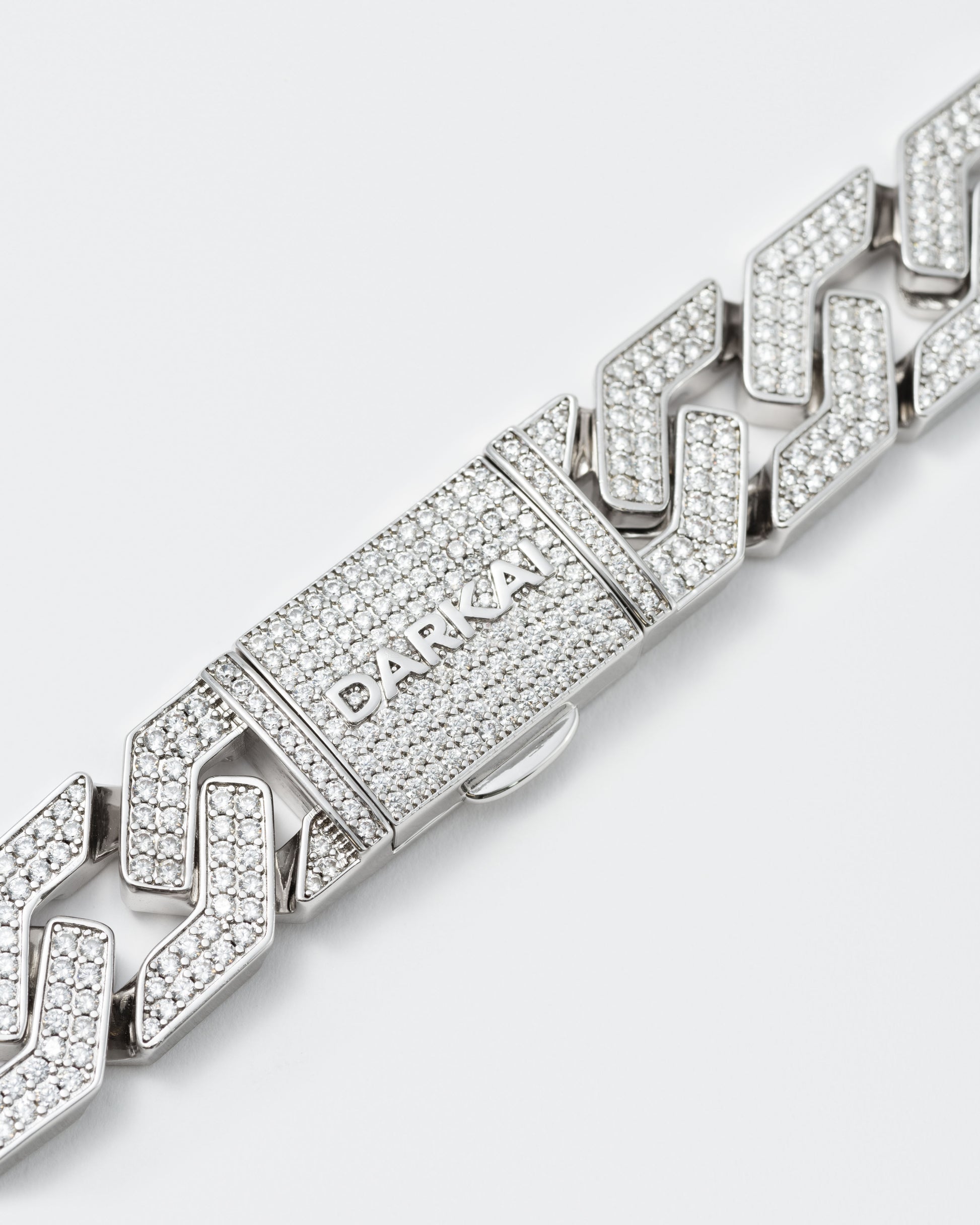 detail of oversize prong chain bracelet with 18kt white gold coating and hand-set micropavé stones in diamond white. Fine jewelry grade drawer closure with logo