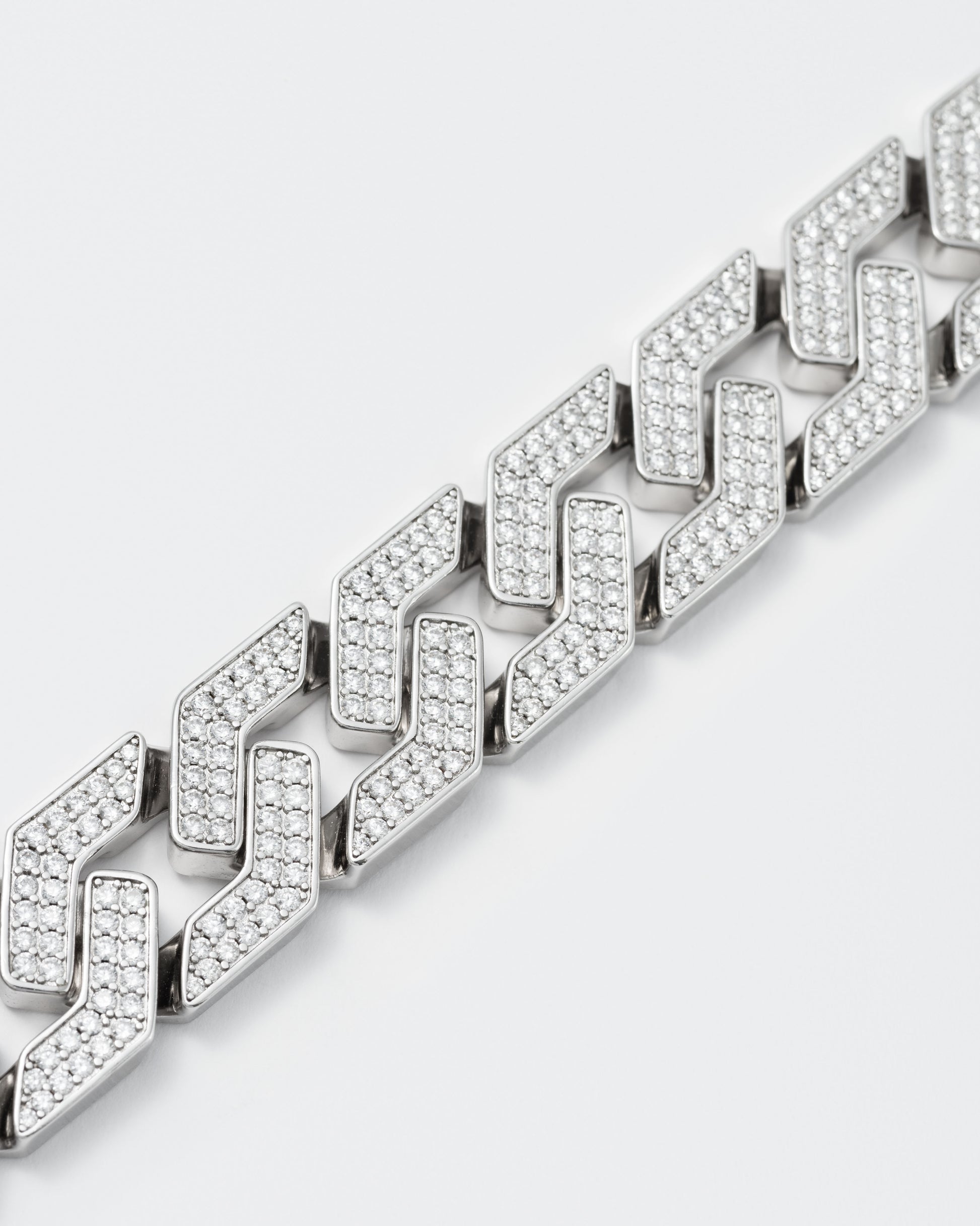 detail of oversize prong chain bracelet with 18kt white gold coating and hand-set micropavé stones in diamond white. Fine jewelry grade drawer closure with logo.