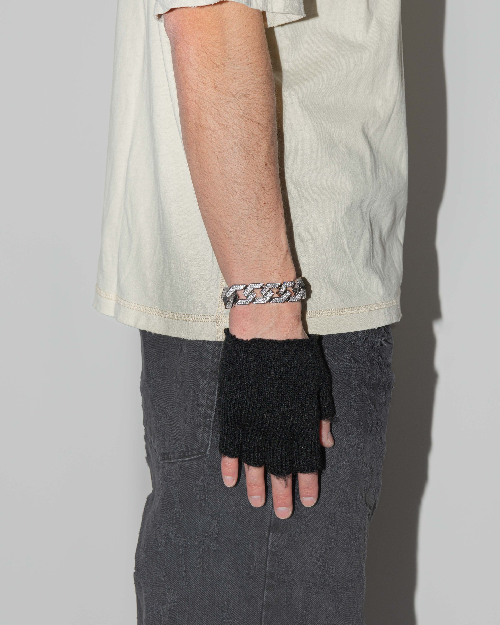 man wearing oversize prong chain bracelet with 18kt white gold coating and hand-set micropavé stones in diamond white. Fine jewelry grade drawer closure with logo