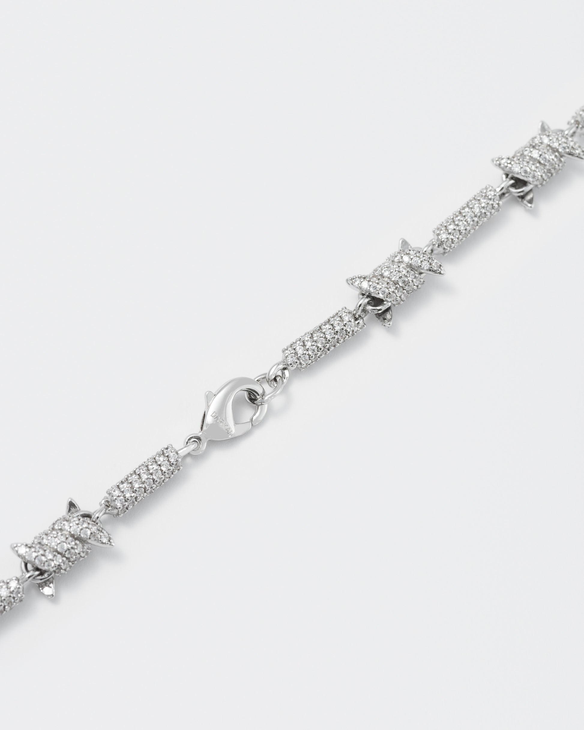 detail of barbed Wire bracelet with 18kt white gold coating and hand-set micropavé stones in diamond white. Lobster clasp closure with logo