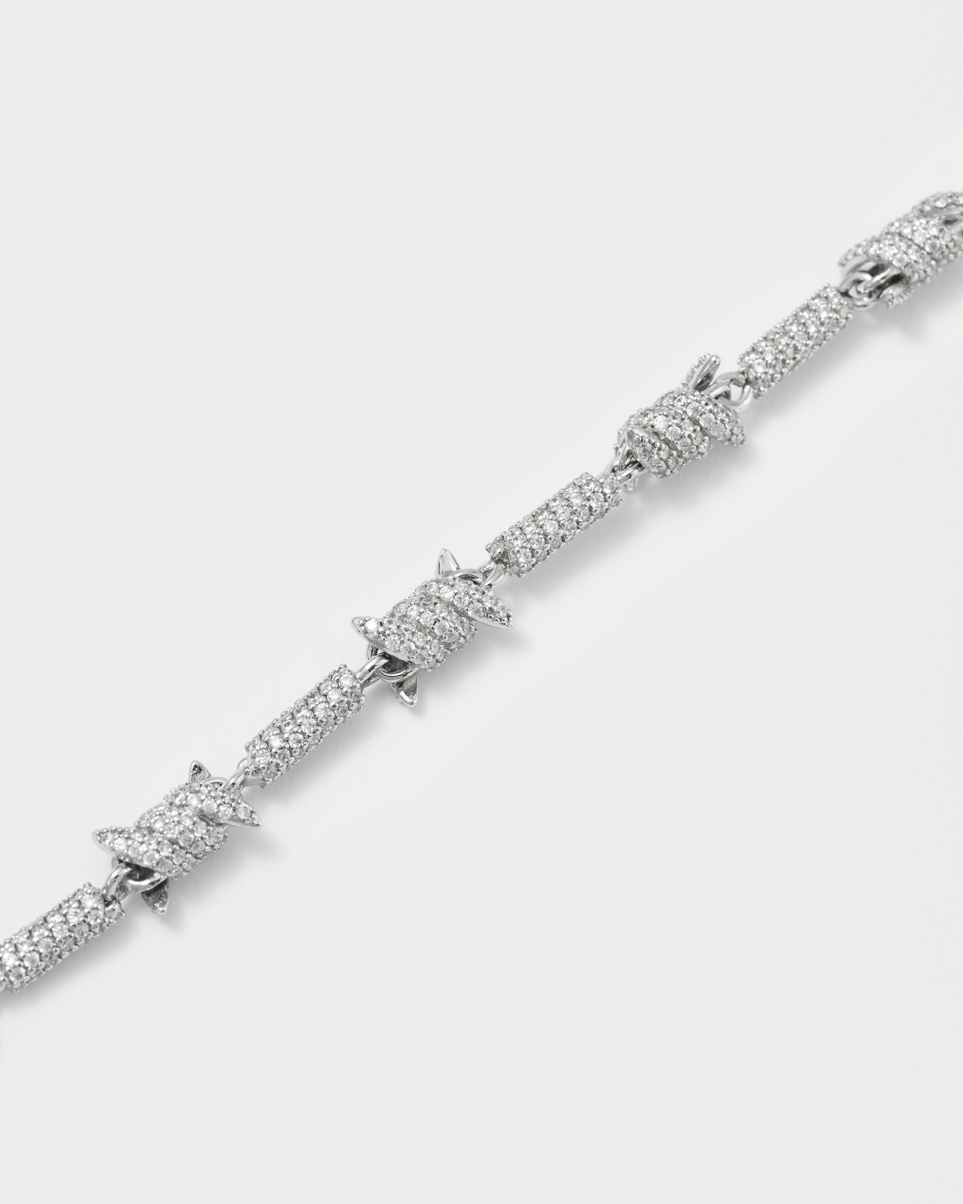 detail of barbed Wire bracelet with 18kt white gold coating and hand-set micropavé stones in diamond white. Lobster clasp closure with logo