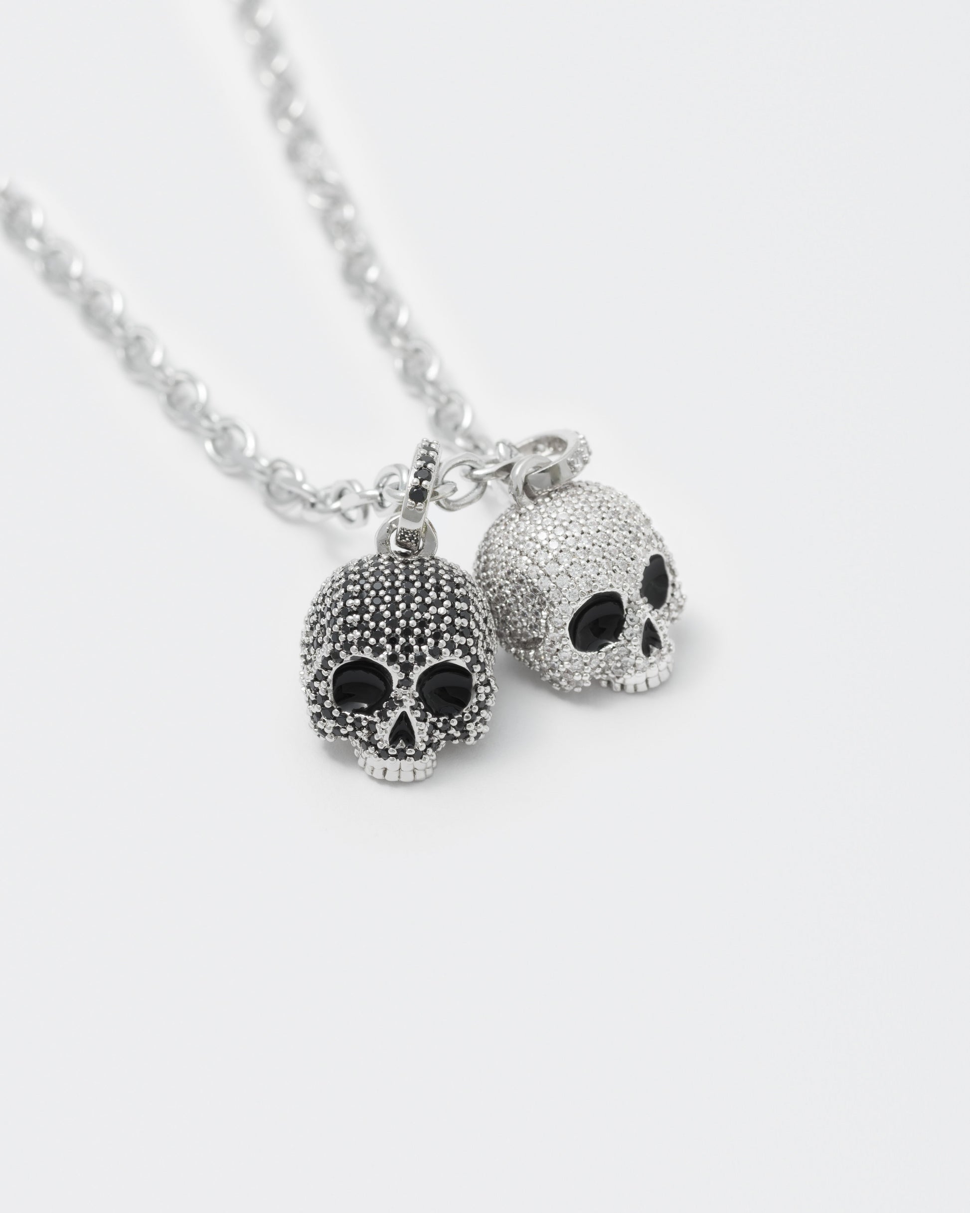 detail of 8k white gold coated skulls pendant necklace with contrasting hand-set micropavè stones in white and black and hand painted black enamel