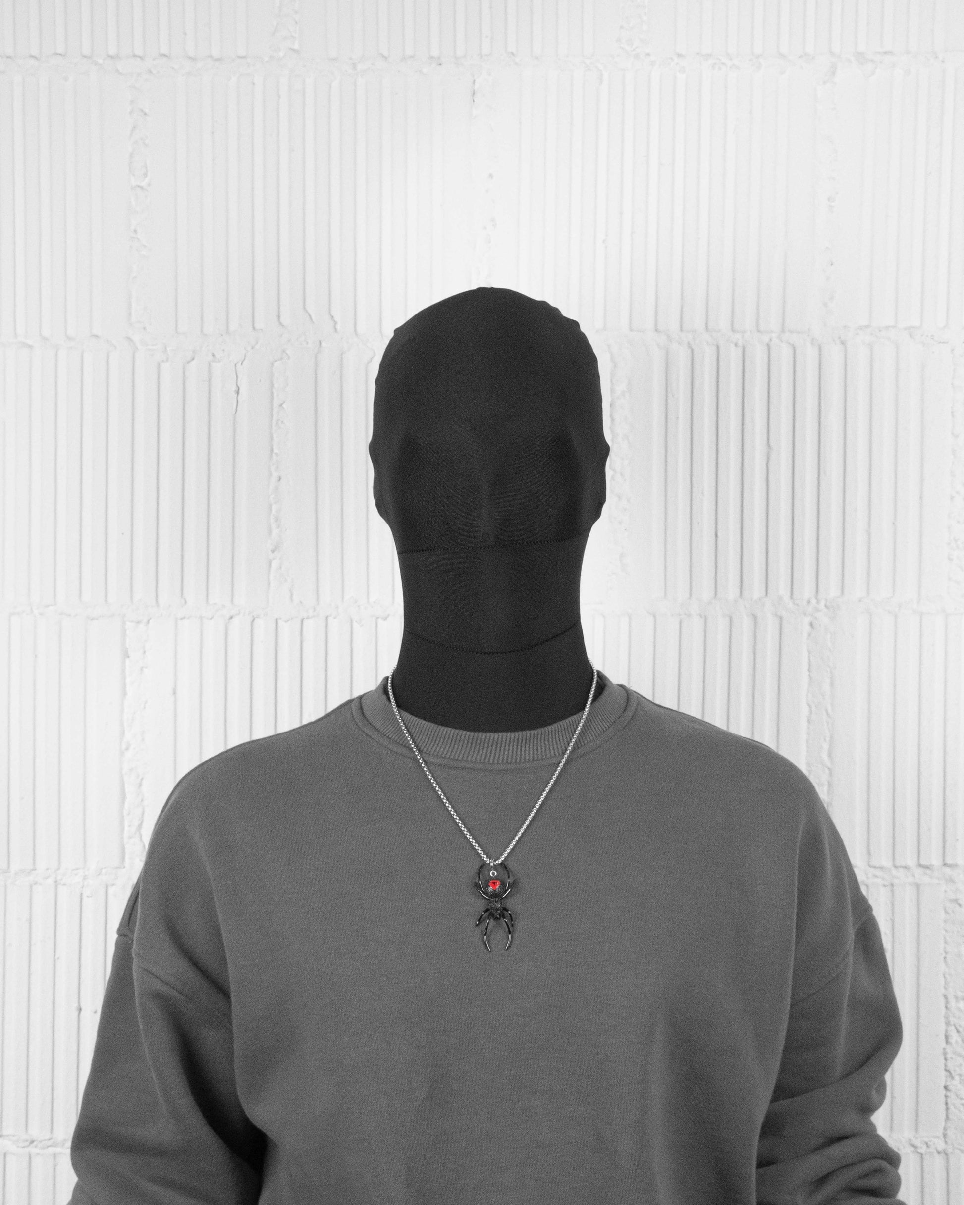 man with black suit wearing Black PVD coated black widow pendant necklace with hand-set micropavé stones in black, metal details, red enamel finishing and 3mm box chain