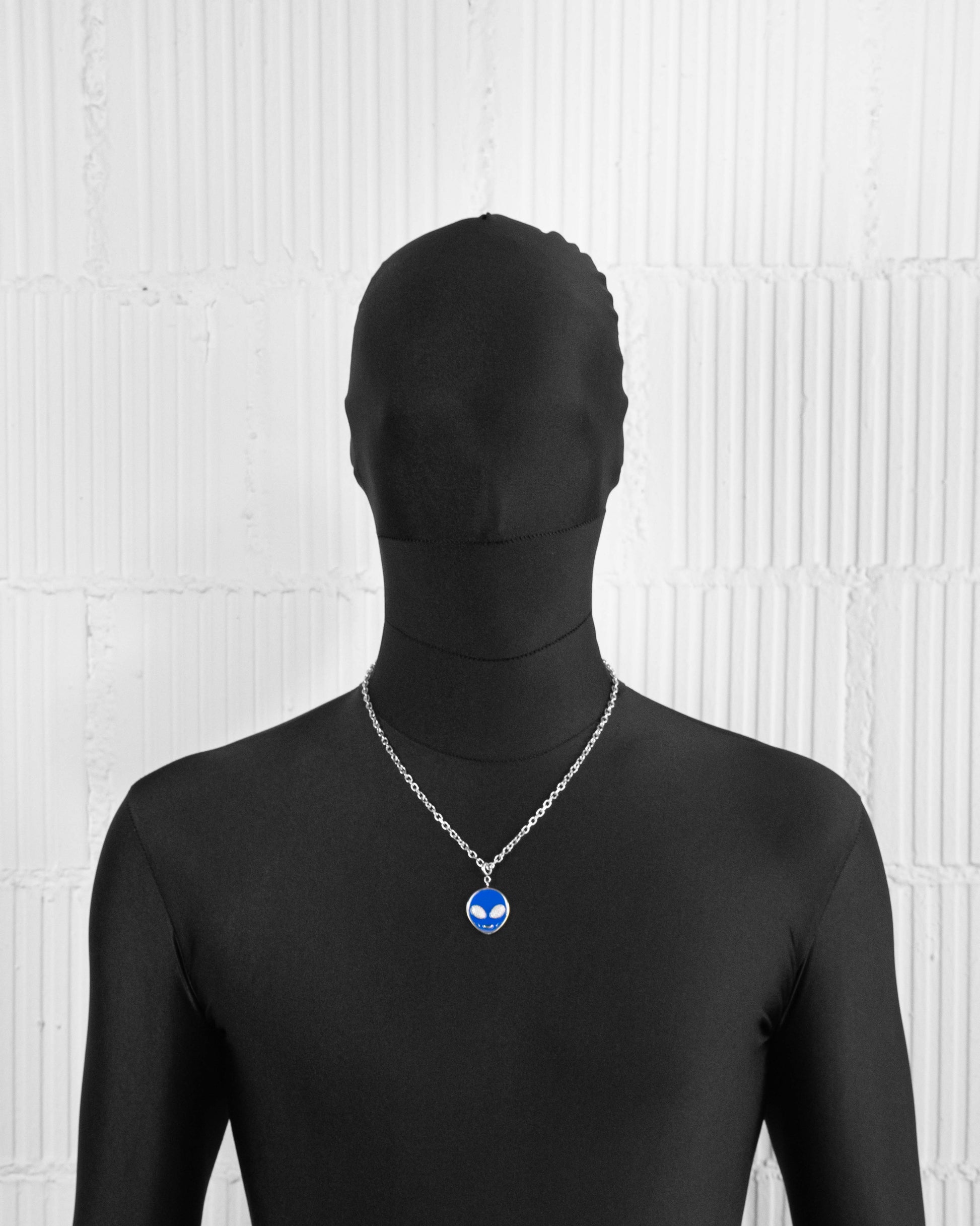 man with black suit wearing 18k white gold coated alien pendant necklace with hand-set micropavé stones in white on blue hand painted glow in the dark alien pendant and 3mm rolo chain