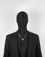 man with black suit wearing 18k white gold coated heart pendant necklace with hand-set micropavè stones in white and green-blue hand painted enamel