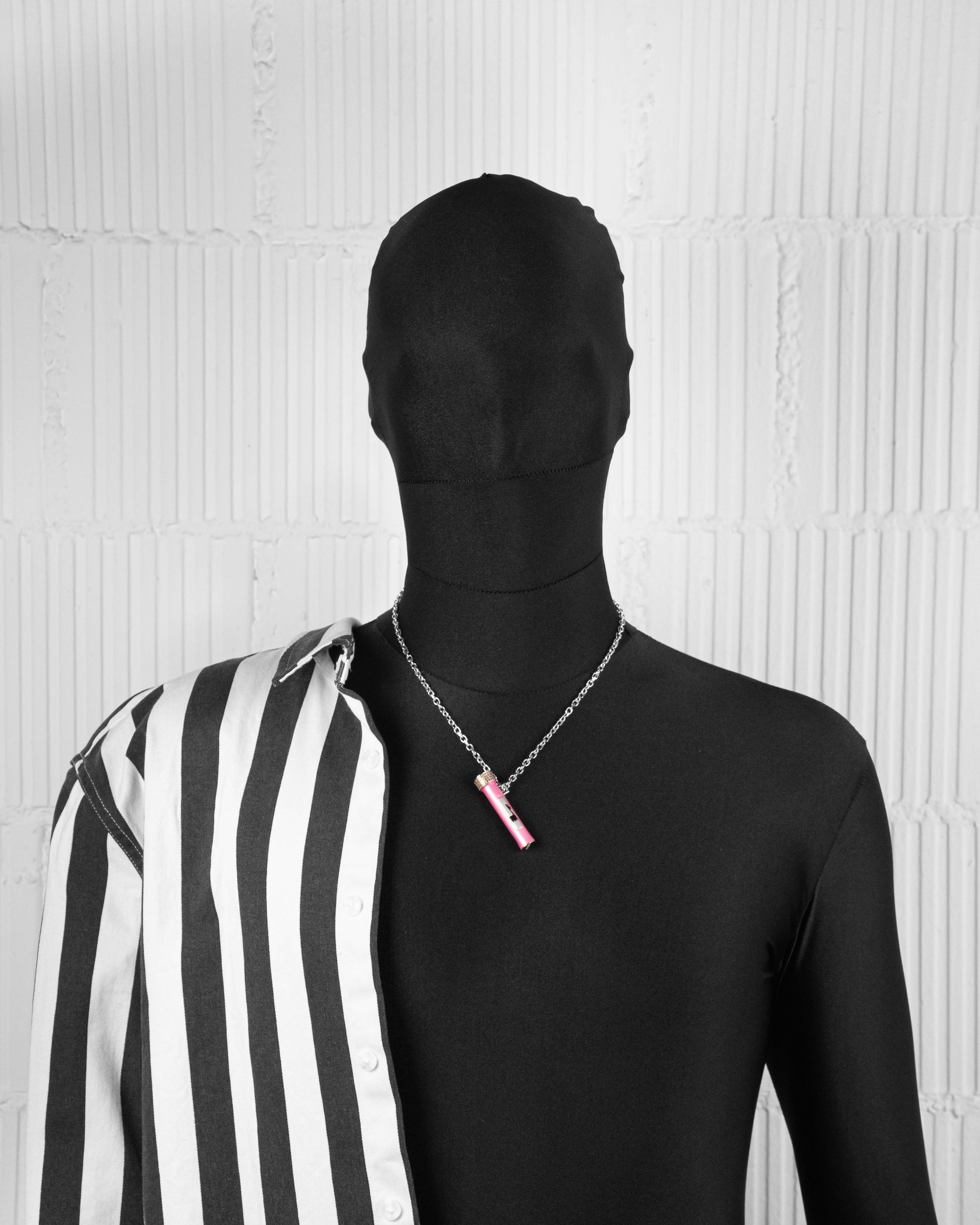man with black suit wearing 18k white gold coated vial pendant necklace with hand-set micropavé stones in coffee, pink enamel and black enamel llama with 3mm rolo chain