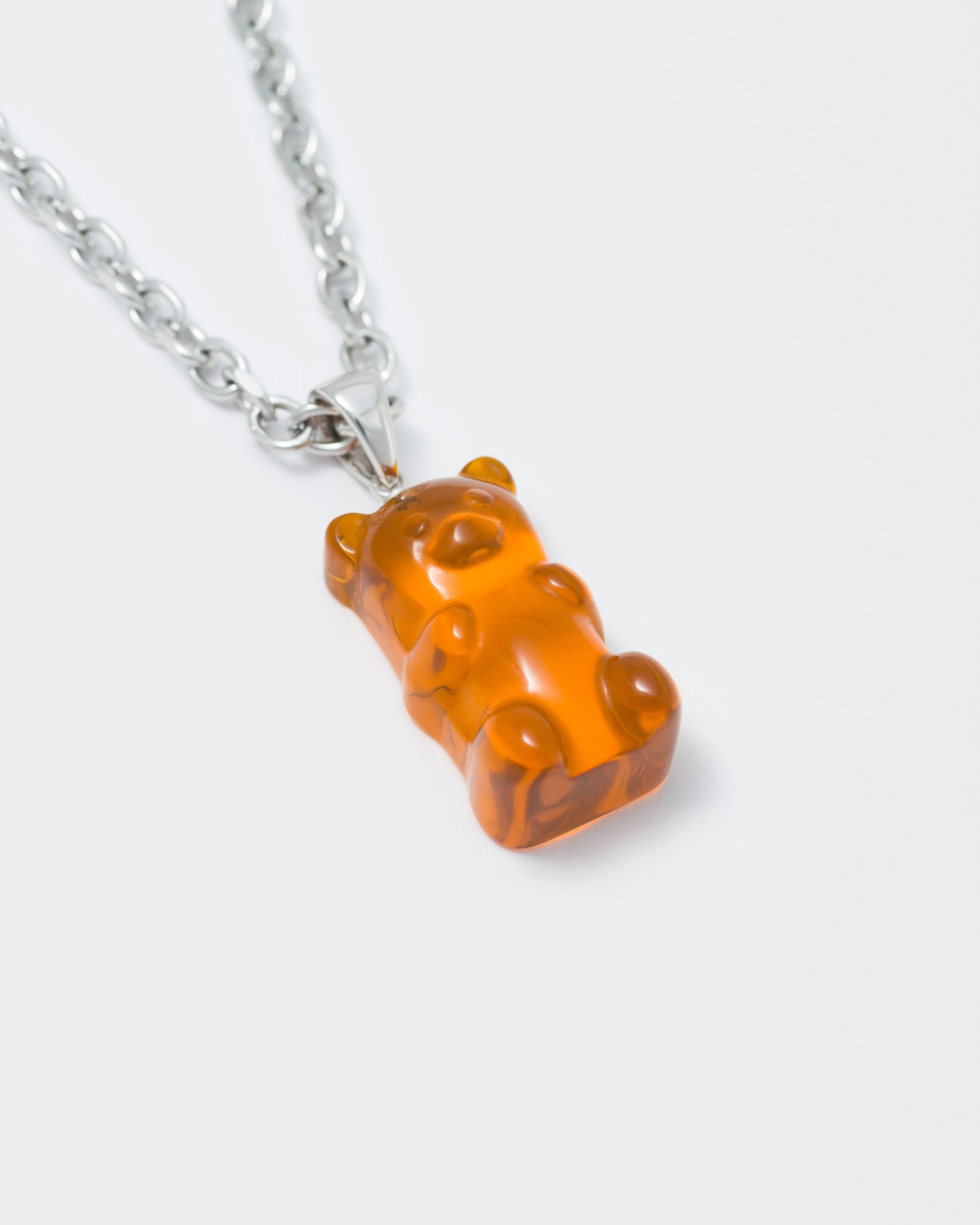 detail of 18k white gold coated gummy bear pendant necklace with 3D cut clear crystal in orange and 3mm rolo chain
