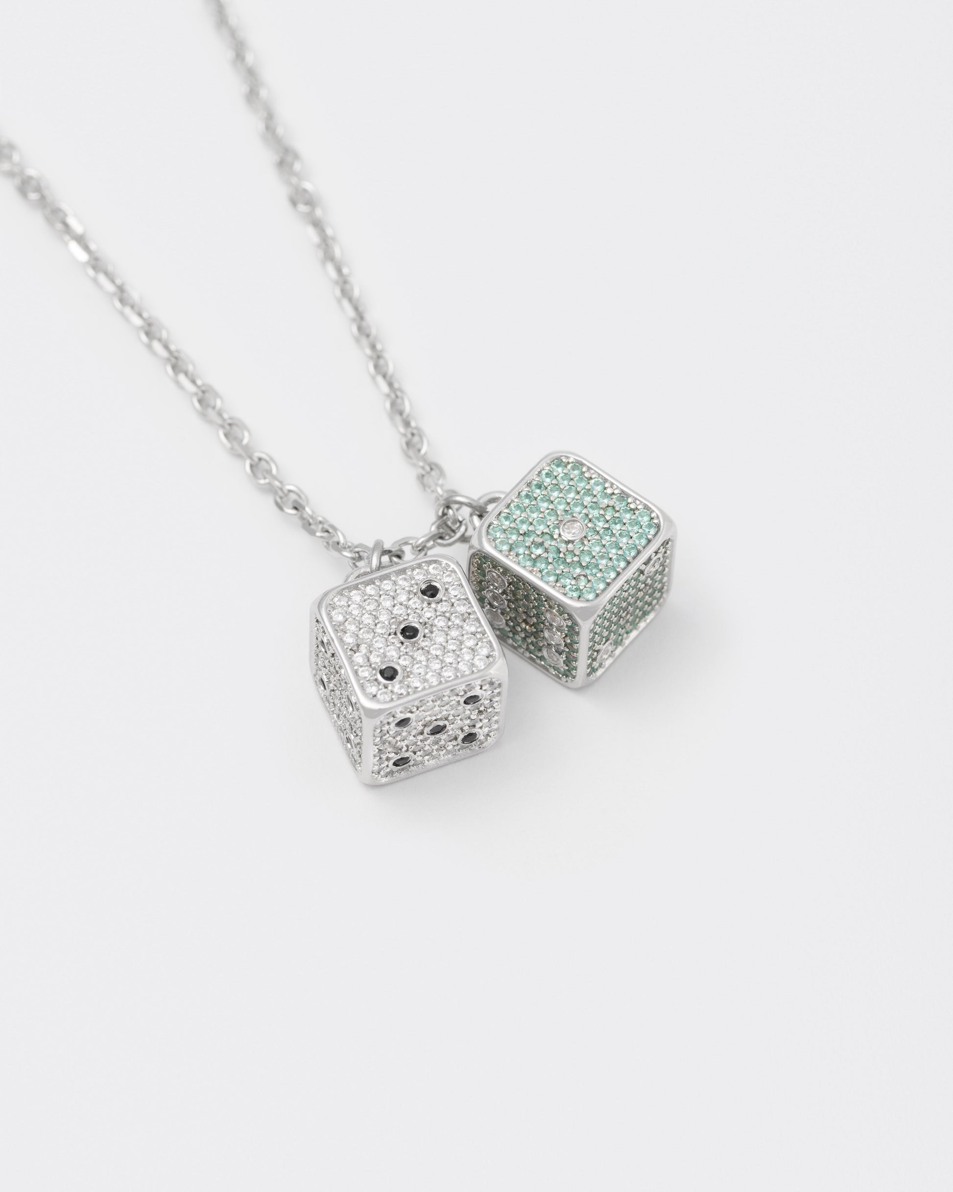 detail of 18k white gold coated asymmetrical dice pendant necklace with contrasting hand-set micropavè stones in white and tourmaline and counting dots in black and white stones
