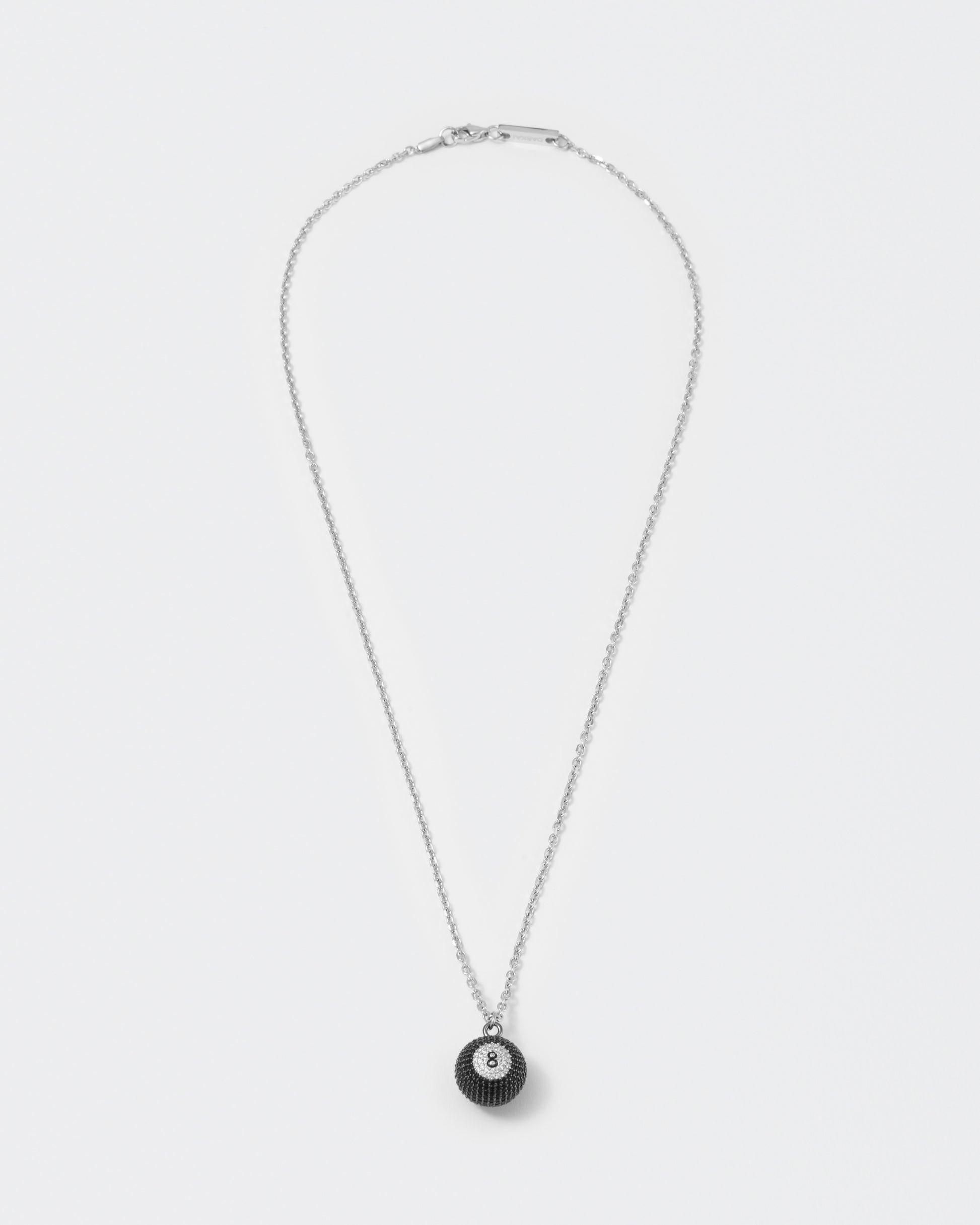Eight ball pendant necklace with deep black PVD coating and hand-set micropavé stones in black and diamond white. Hand painted number 8 in black enamel. 2mm cable chain and lobster clasp with metal logo tag