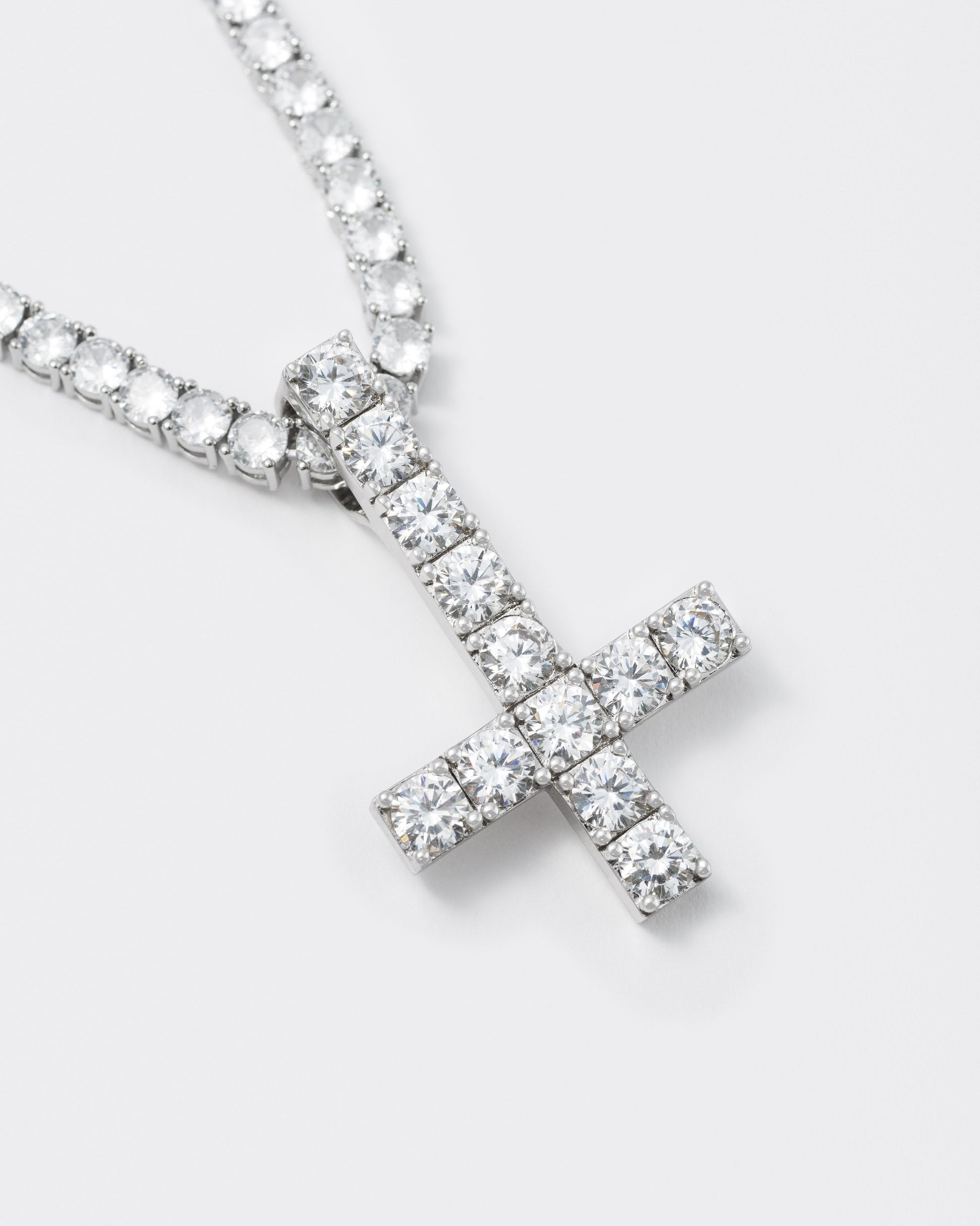 Detail of detail of 18k white gold reversed coated cross pendant necklace with hand-set stones in white and tennis chain