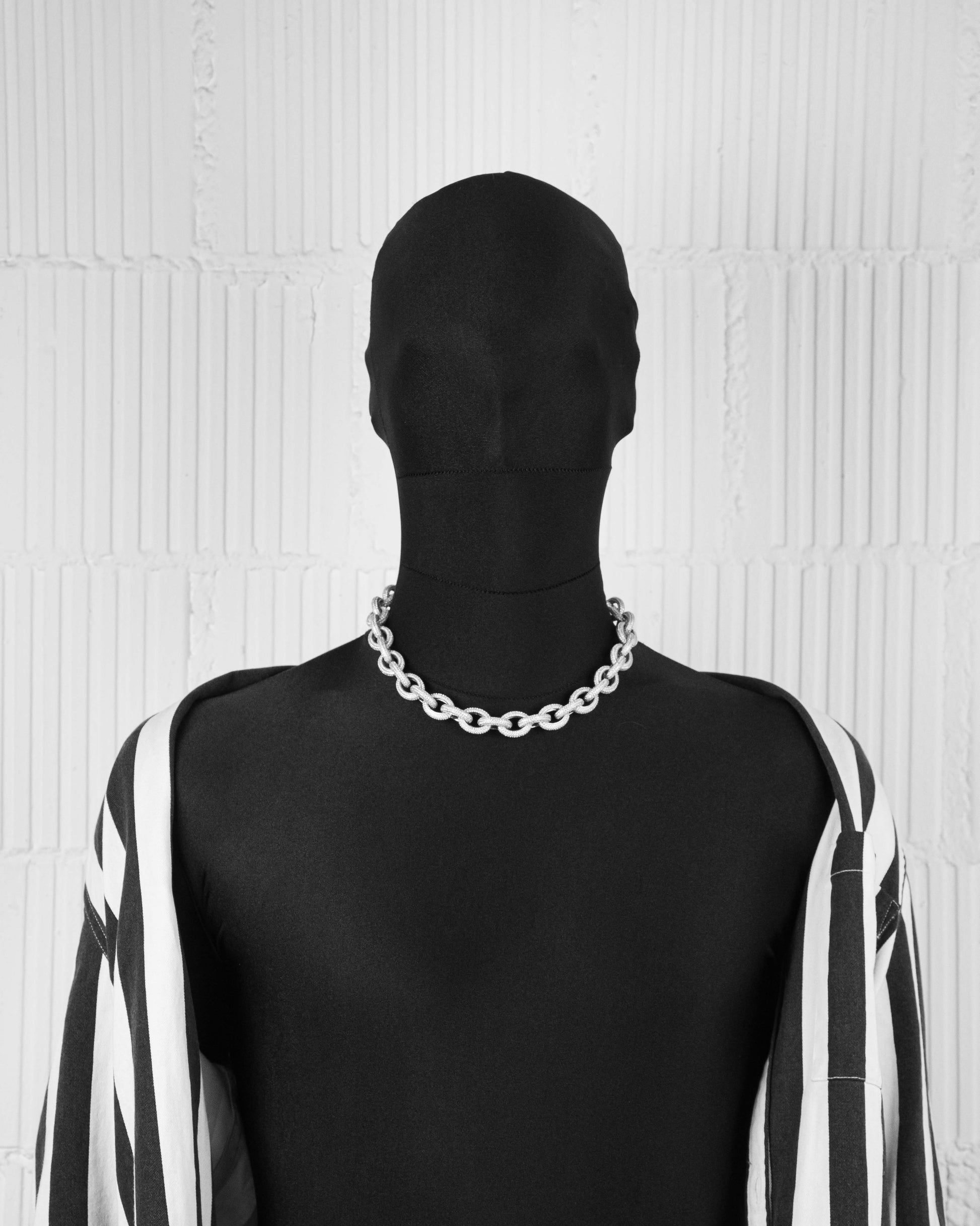 man with black suit wearing 18k white gold coated oversize rolo necklace with all around hand-set micropavé stones in white