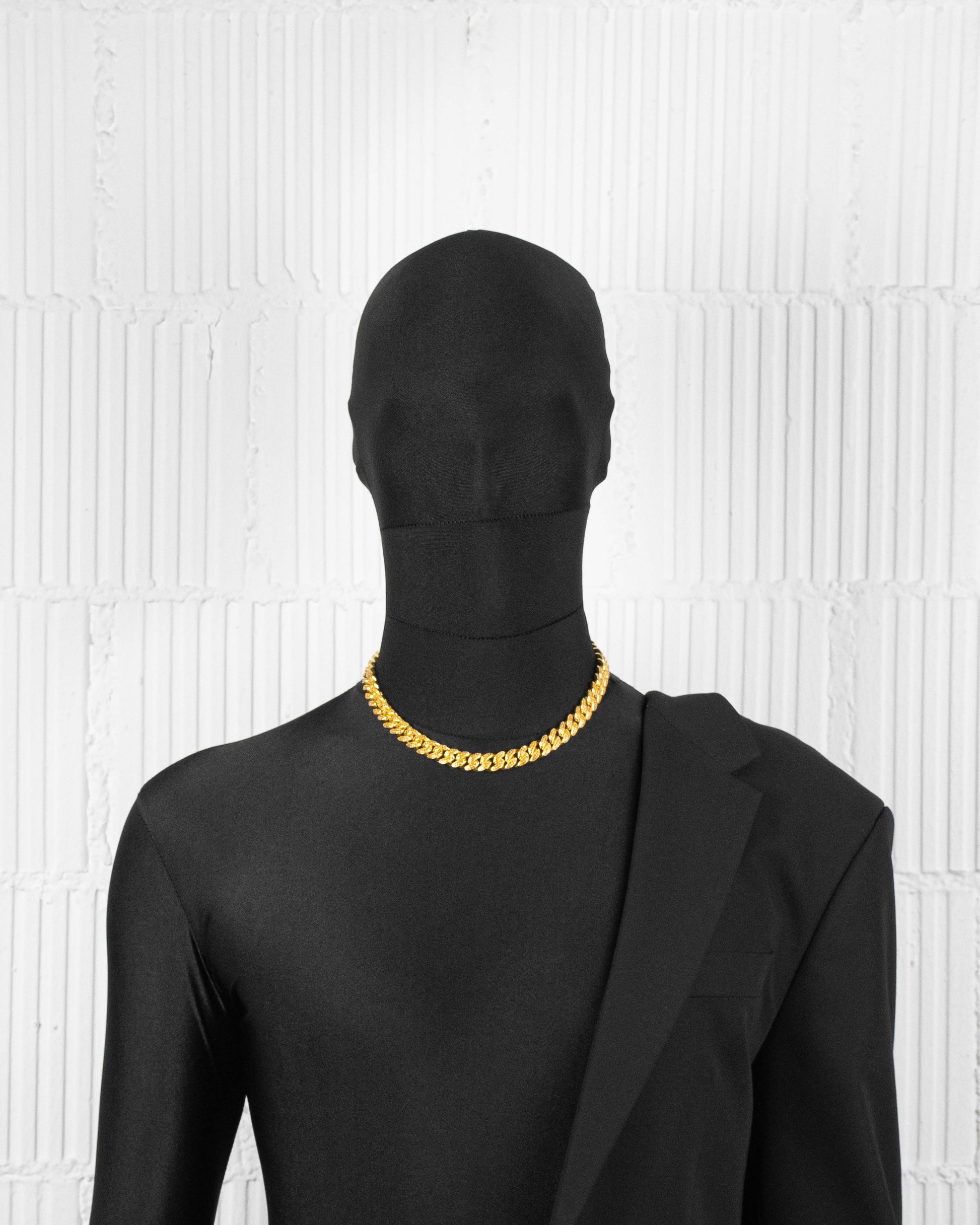 man with black suit wearing 18k yellow gold coated cuban chain necklace with hand-set micropavé stones in tiger yellow