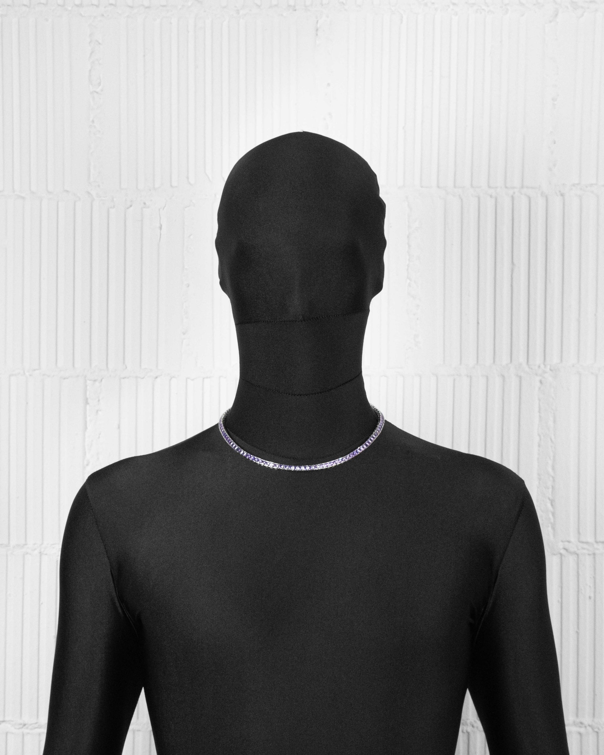 man with black suit wearing 18k white gold coated tennis chain necklace with hand-set princess-cut stones in amethyst purple