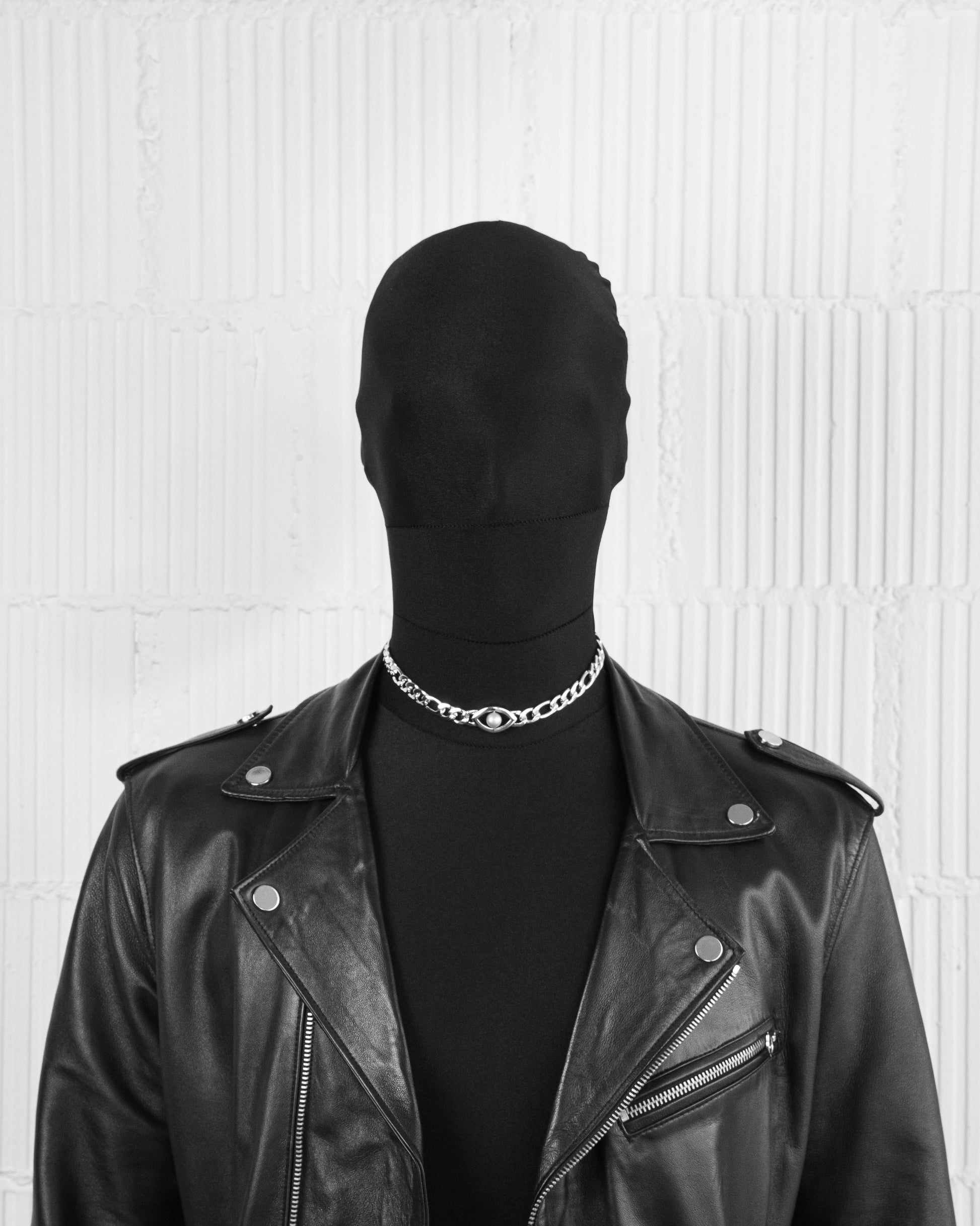 man with black suit wearing 18k white gold coated figaro chain choker with central natural indonesian freshwater pearl in mabe grey and oversize carabiner clasp with lasered logo.