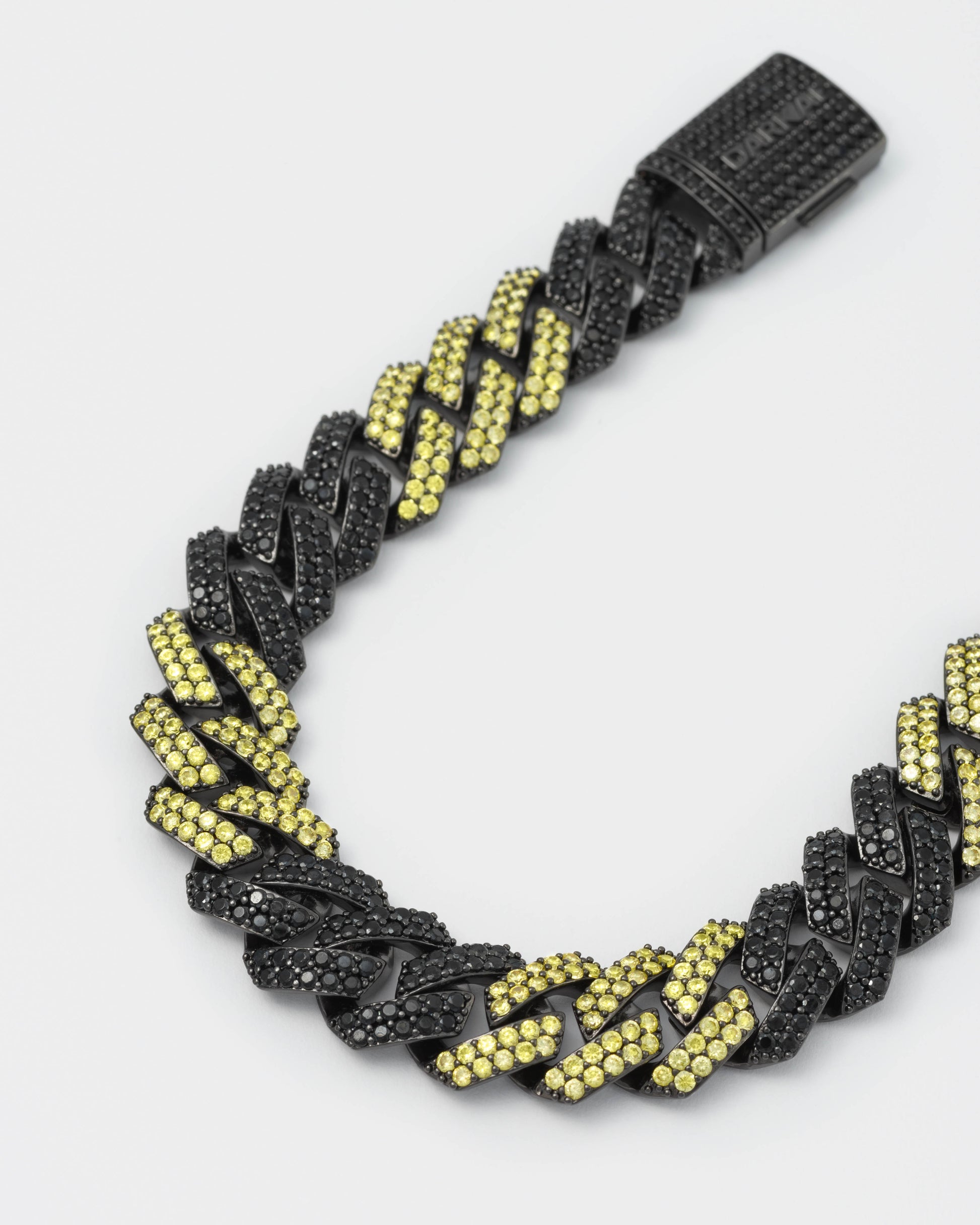 detail of prong chain necklace with deep black PVD coating and hand-set micropavé stones in black and golden yellow. Fine jewelry grade drawer closure with logo