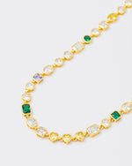 detail of 18k yellow gold coated mixed bezels chain necklace with hand-set stones in different shapes and colors. Mix of rectangular, square, round and heart-shaped stones in white, amethyst, emerald green and gold yellow