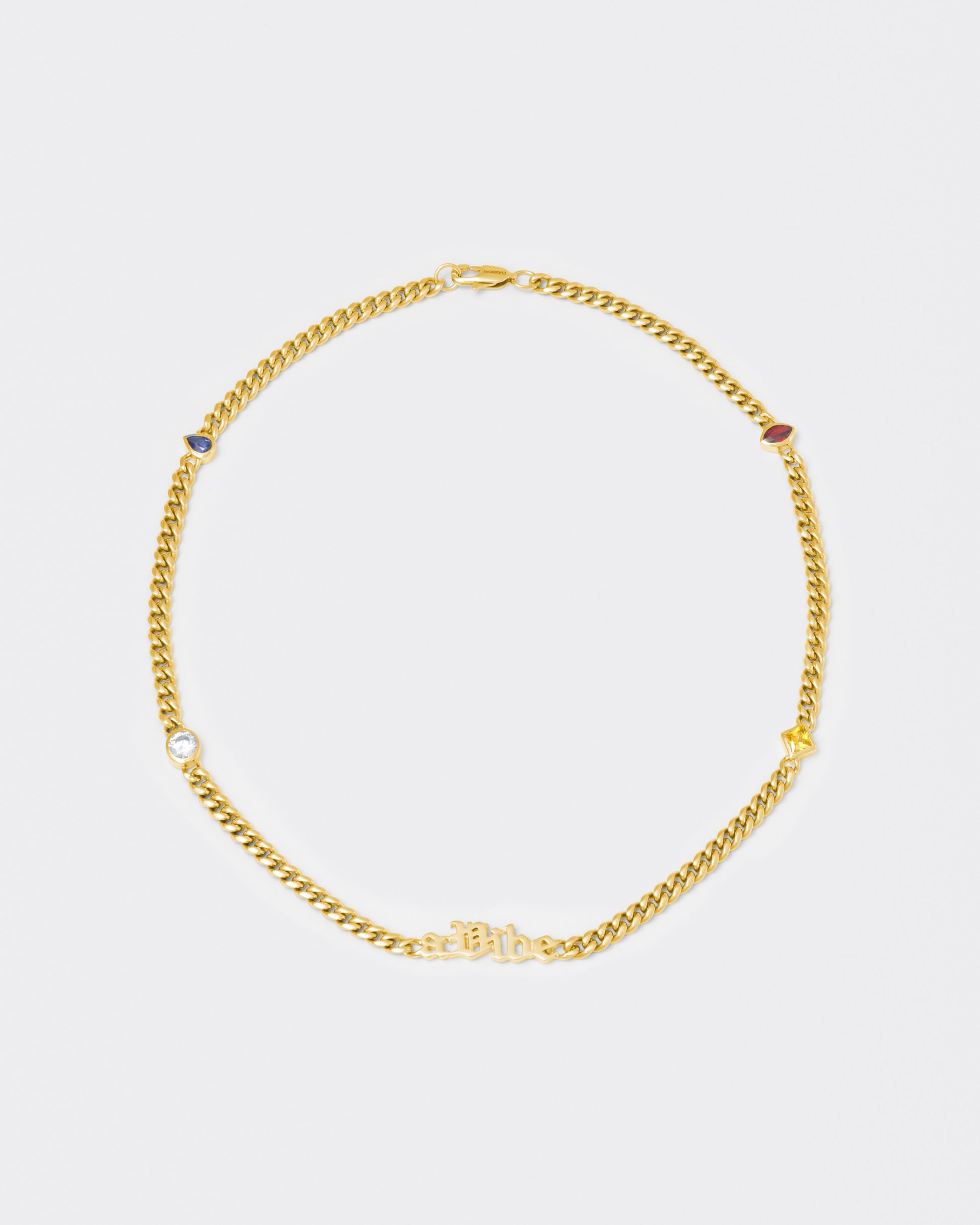 A Vibe cuban chain necklace with 18kt yellow gold coating, mixed shape bezel stones in diamond white, yellow, garnet, tanzanite and "A Vibe" central metal tag. Lobster clasp with logo