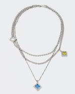 triple layer chain necklace with 18kt white gold coating and rhombus shaped pendants with princess-cut stones in diamond white, sapphire blue, olive and dark champagne