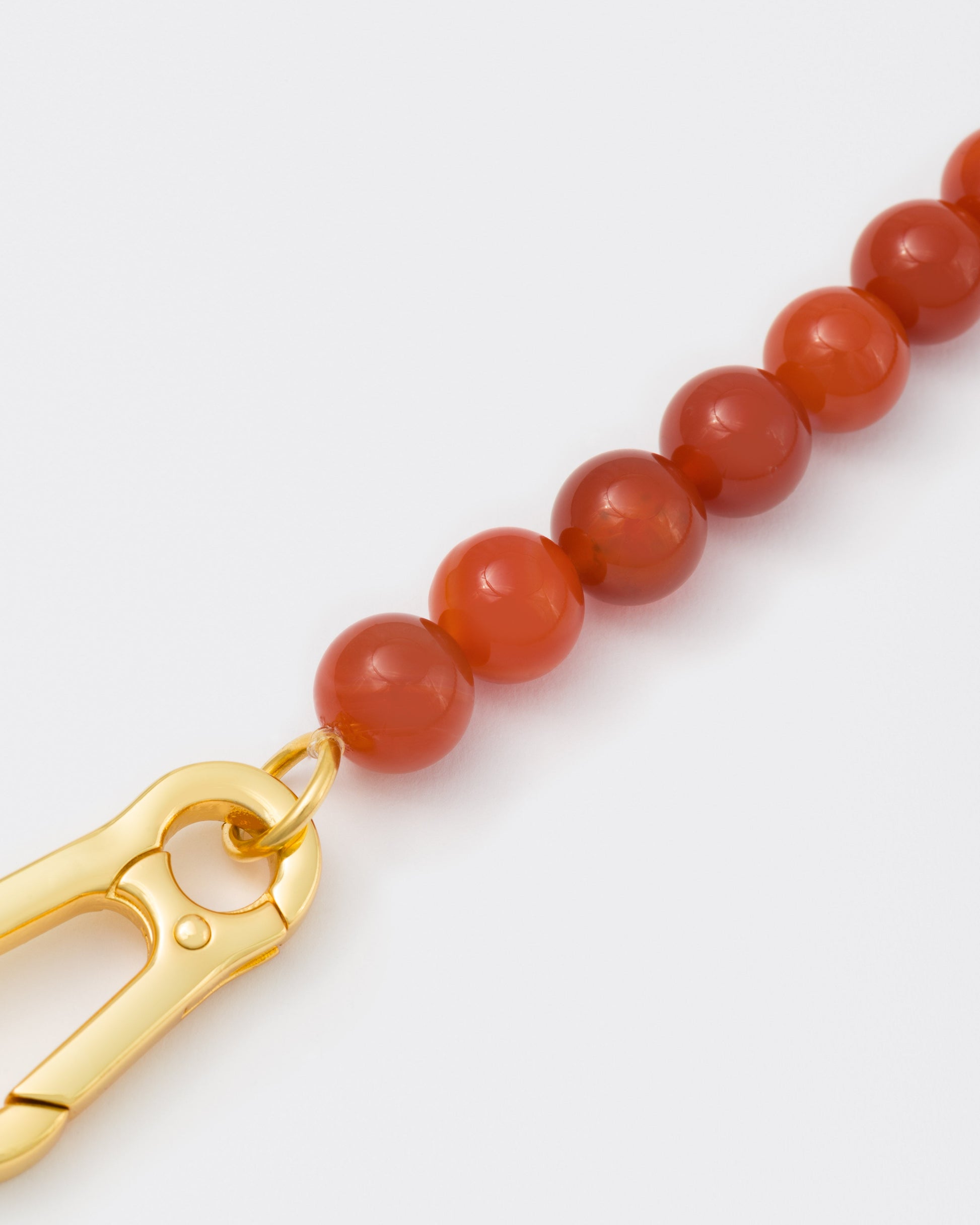 detail of Amber stones necklace with 18k yellow gold coated lasered logo oversize carabiner clasp.