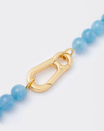 detail of clasp necklace with aquamarine stones necklace with 18k yellow gold coated lasered logo oversize carabiner clasp.
