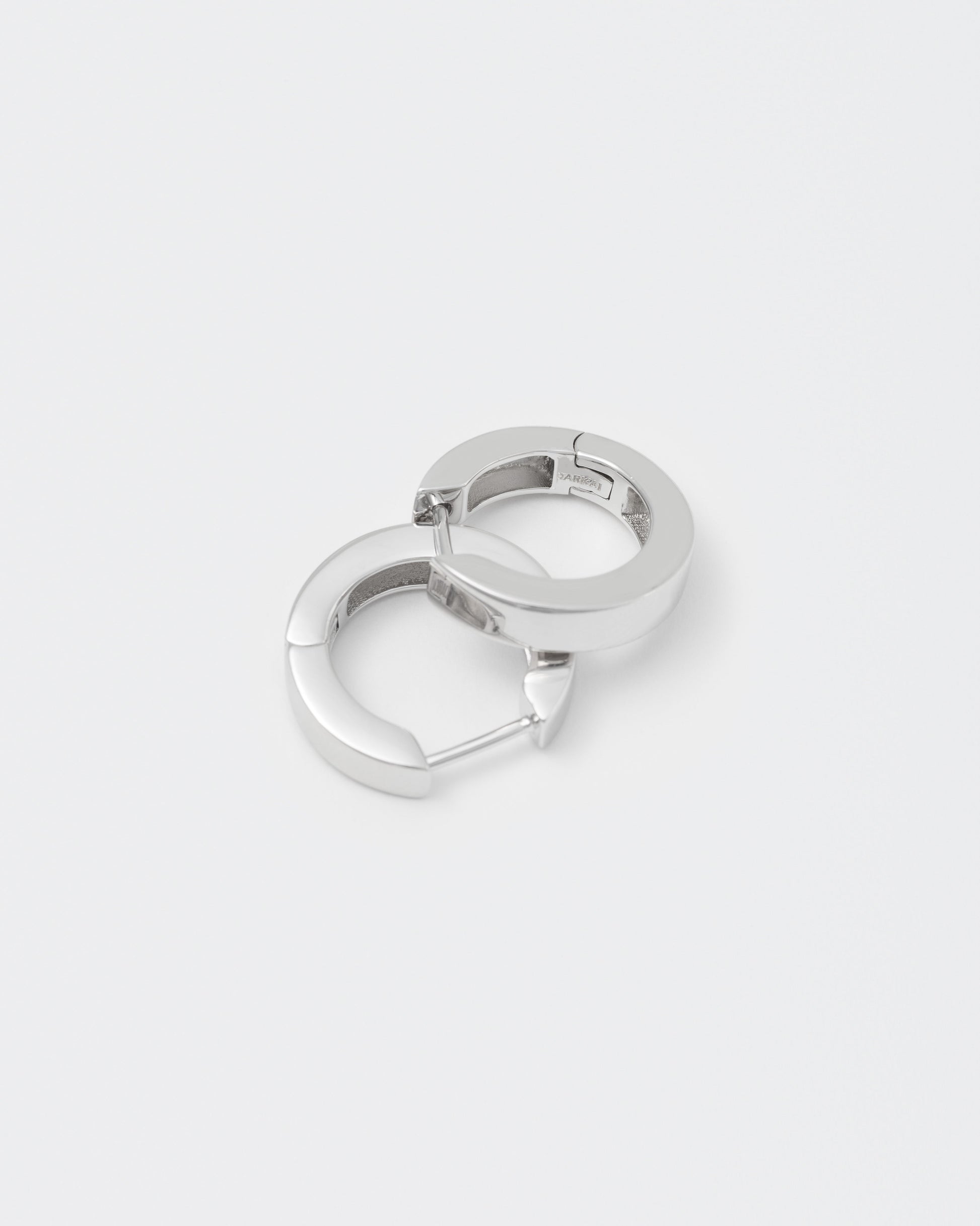 detail of 18k white gold coated hoop earrings with lasered logo and details on the inside
