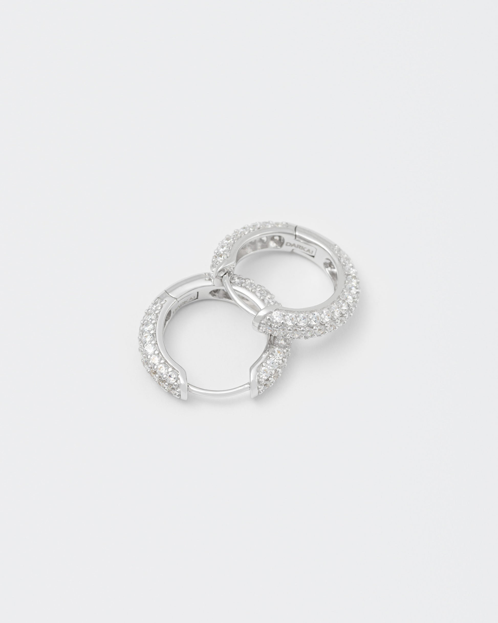 detail of 18k white gold coated hoop earrings with all around hand-set micropavé stones in white and lasered logo on the inside.