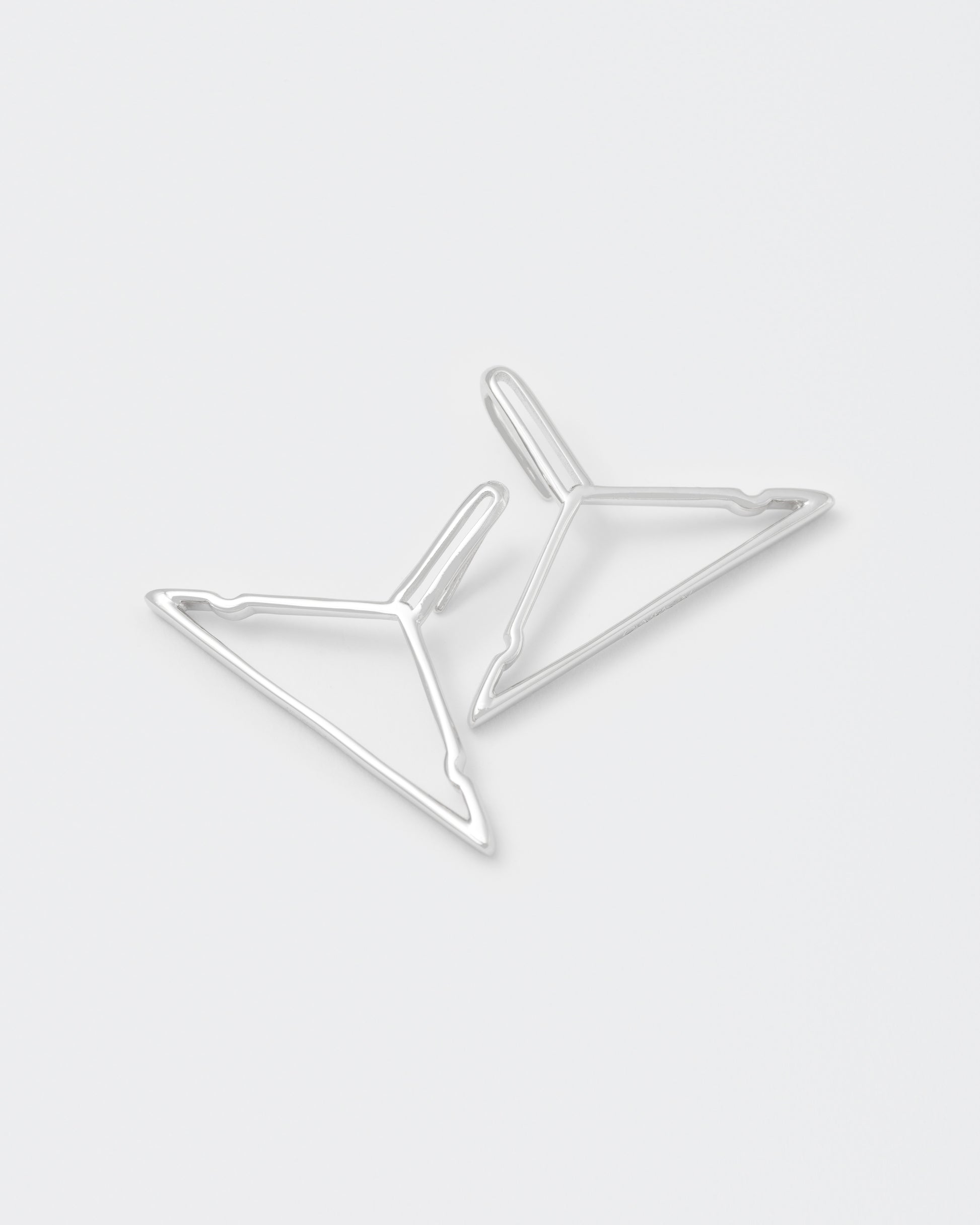 detail of hanger shaped earrings with 18kt white gold coating, silver 925 pin and engraved logo.